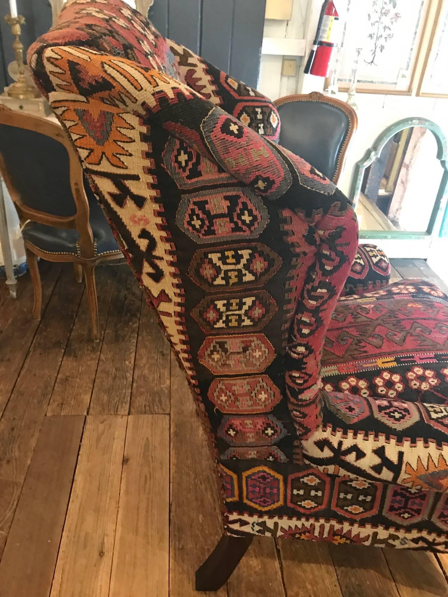 Classic wing chair by George Smith, with wonderful multicolored Kilim upholstery in brown, rasberry, cream, gold, blue and pink. It's the chair that steals the show with it's rich character and warm lively color palette. Dark mahogany handsome