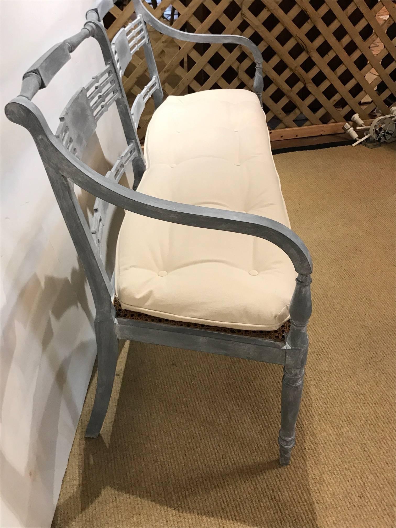 Beautiful bench or loveseat painted a soft Gustavian grey having detailed carved wood back, six turned wood legs, a caned seat with custom new tufted white duck cushion that attaches to the cane bottom.

Measures: Seat 18