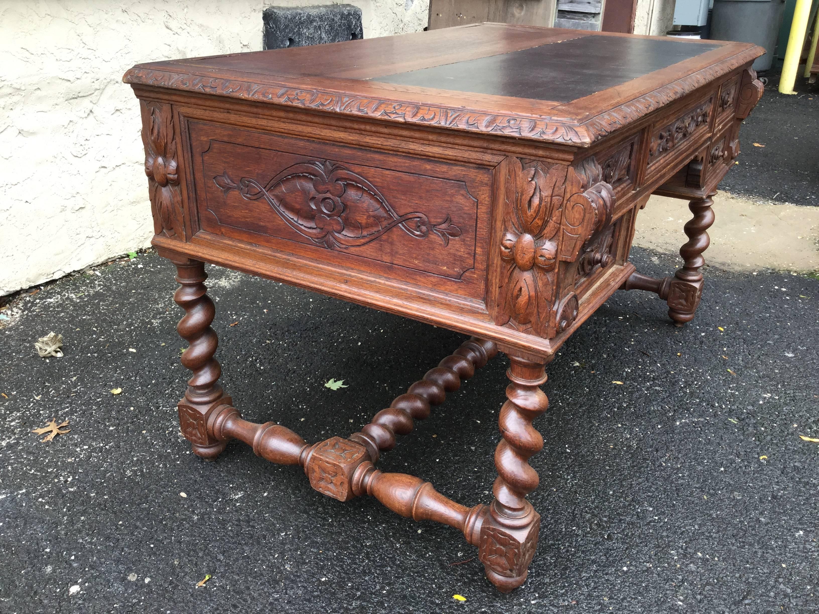 19th century desk on turned barley-twist legs with ornate carvings on all
the drawer fronts. The top work surface, which is covered in black
leather, can be pulled out for more work space. Each drawer has original
locks and hardware.  Back of desk