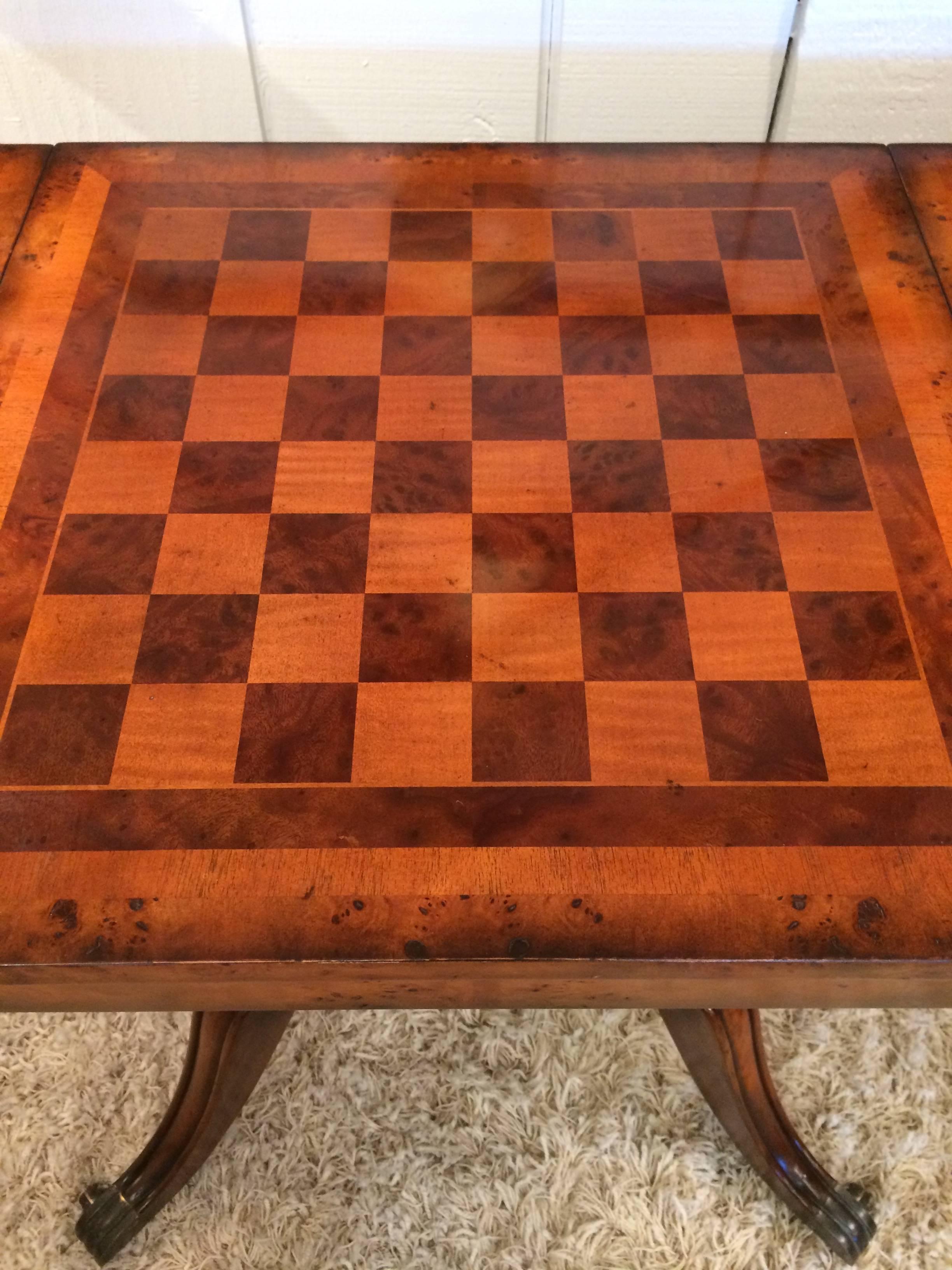 Stunning game table with checker board top that flips over to a tooled leather top, and when removed reveals a sunken backgammon board. Beautiful base with splayed feet on casters with brass sleeves. Four little drawers, two on each side, and a full