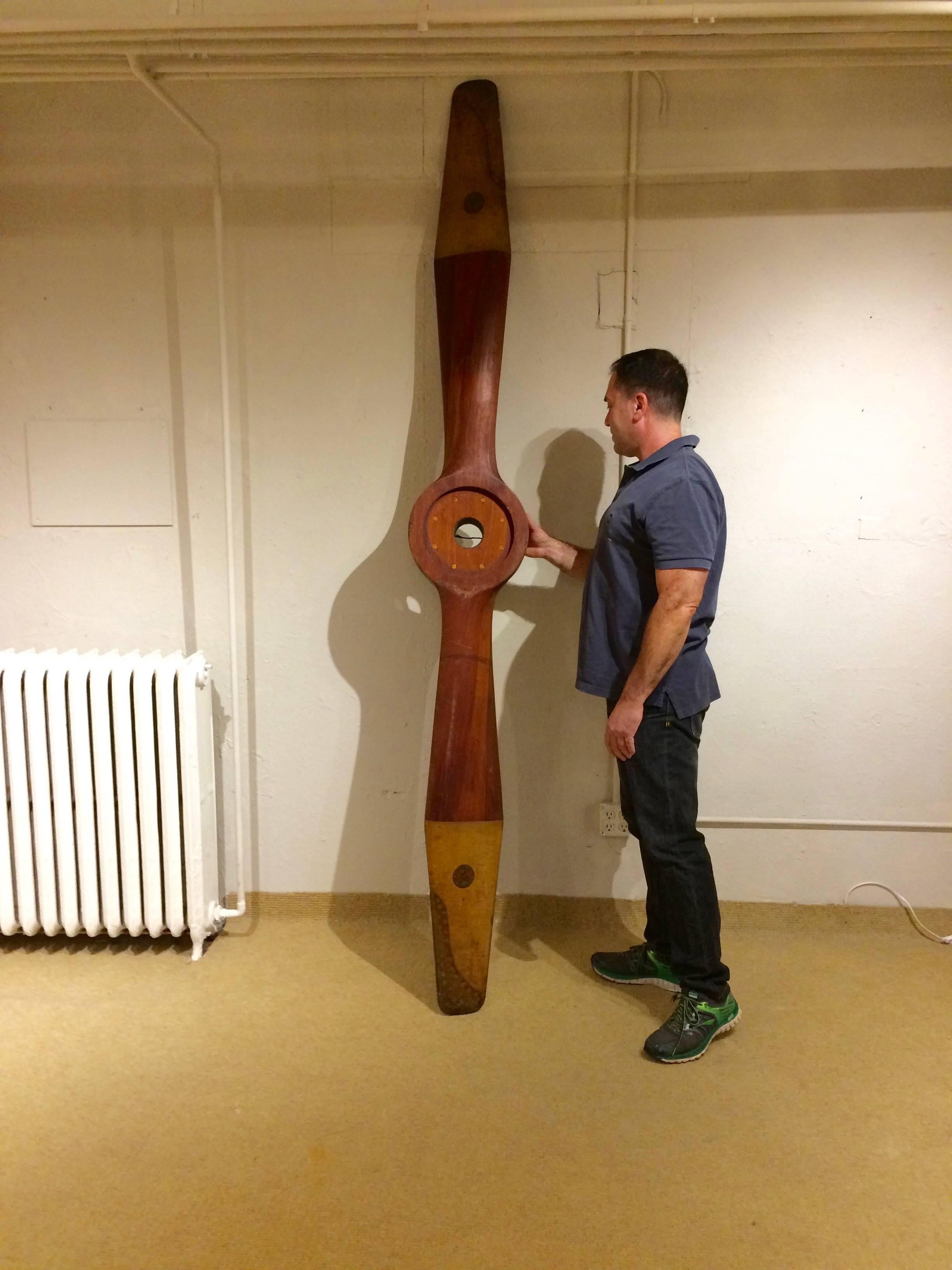 One of a kind enormous mahogany World War II navy plane propeller, sculptural as a found object to hang vertically or horizontally, with rich coloration and copper clad tips, as well as original Unit Construction Co. emblems and engraved serial