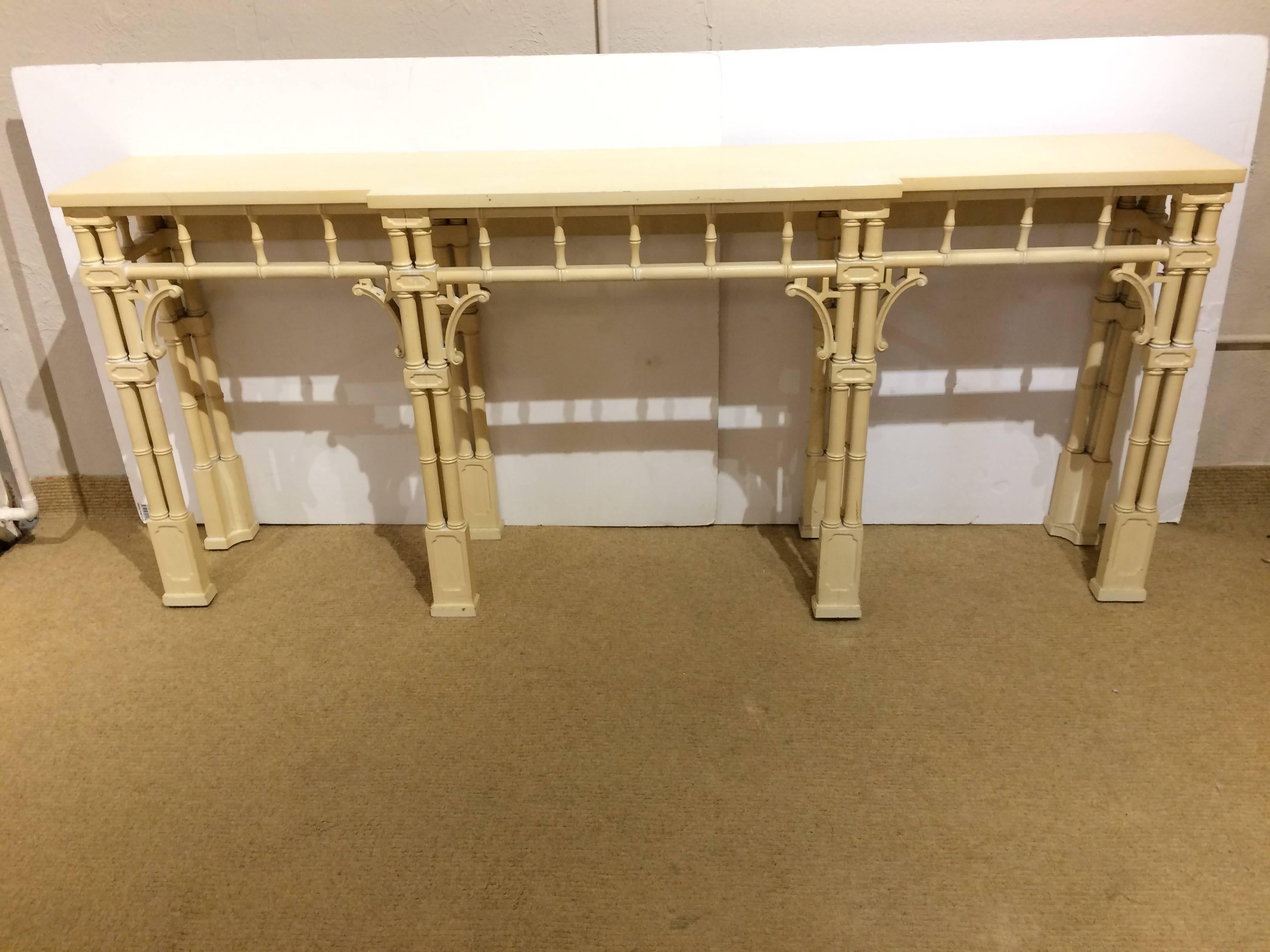 Striking painted wood console table in pale yellow, having glamorous faux bamboo style base and legs.