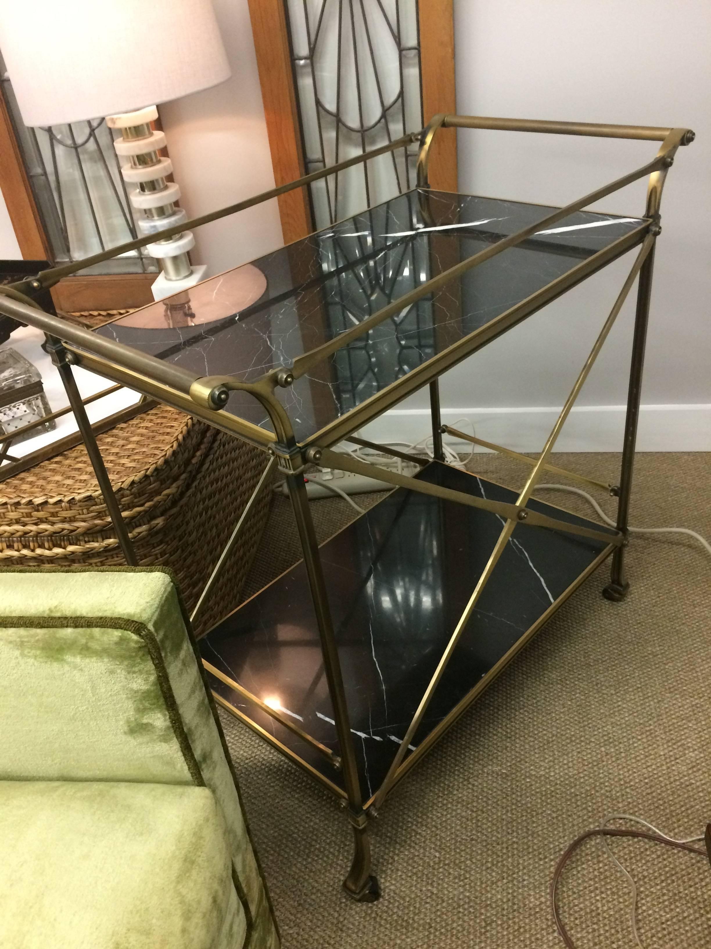 Very handsome well constructed heavy bar cart with neoclassical design having a brushed metal structure and two black with white veined marble inserts. On casters.