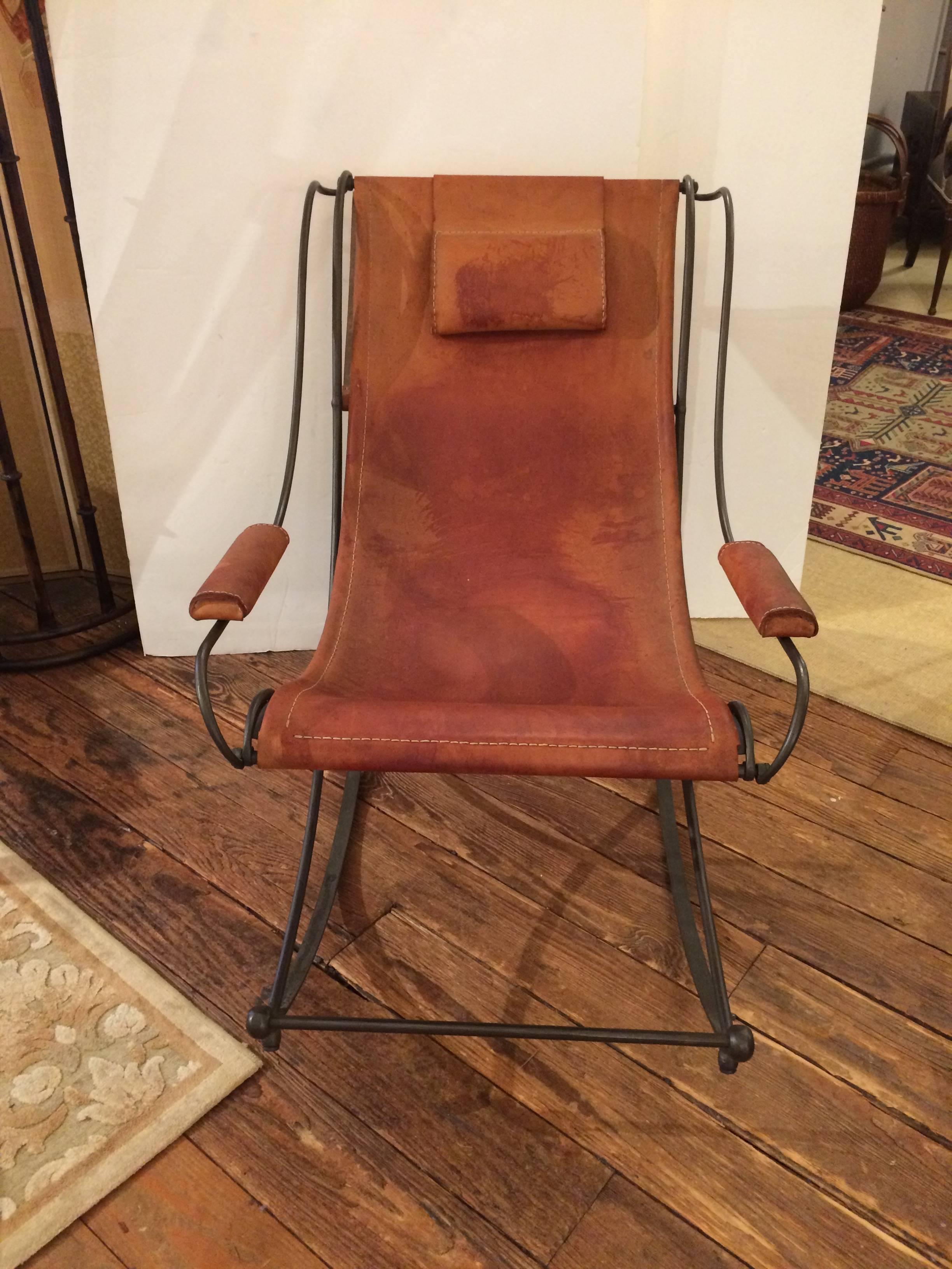 Chic sculptural rocking chair with wonderful Silhouette having a wrought iron base and cognac stitched heavy leather sling back designed seat, padded arms and headrest.