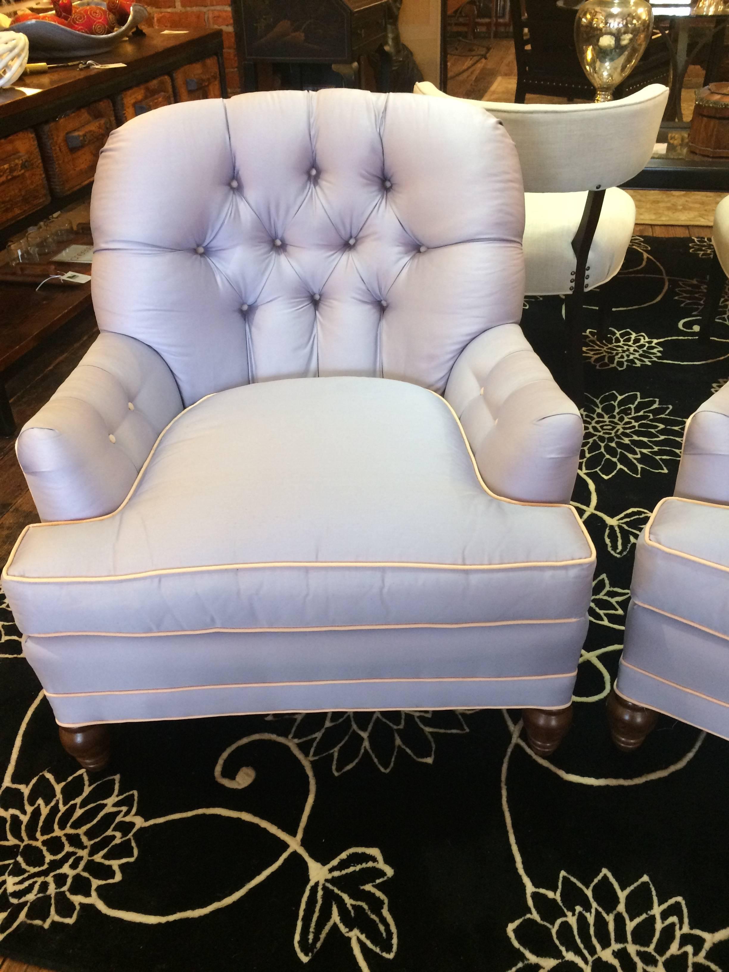 A chic pair of club chairs in a heavenly shade of light blue lavender having tufted backs and arms and cool white piping.