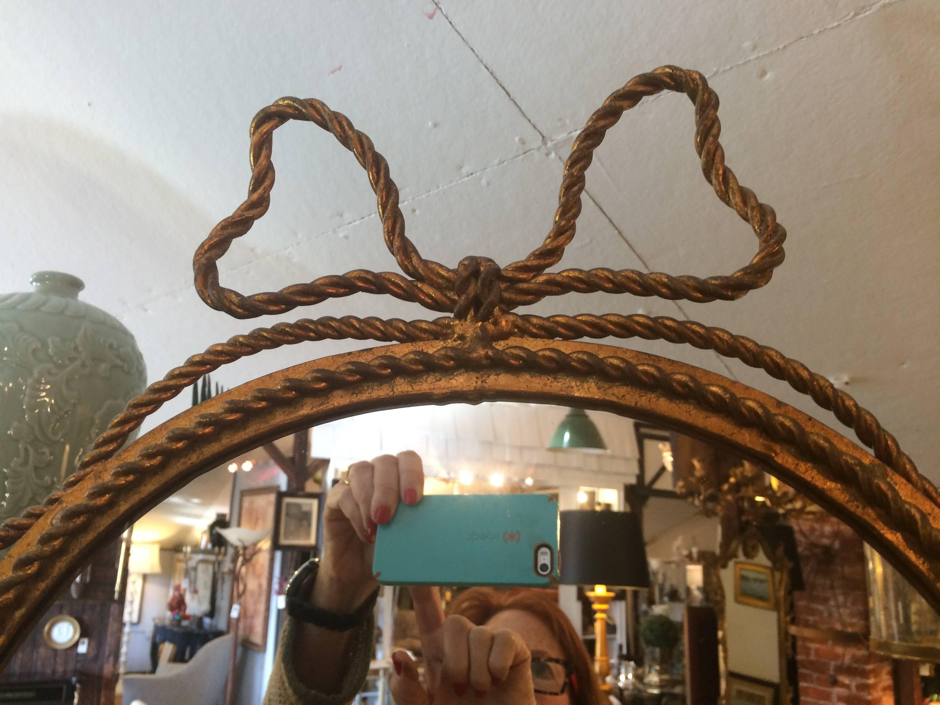 Charming giltmetal floor mirror having curlicues on a pretty stand and lovely bow at the top.