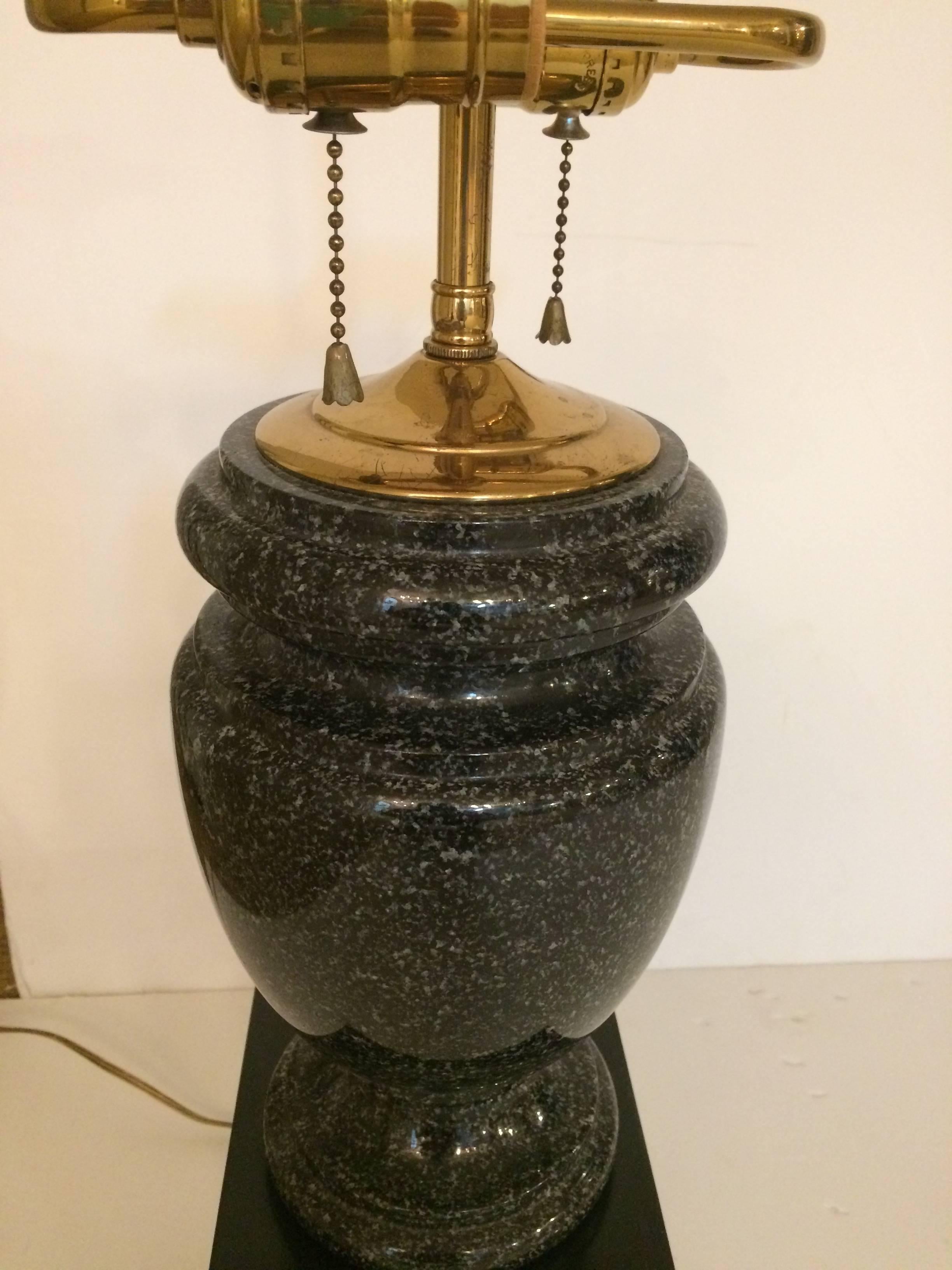 Two very substantial heavy masculine lamps having classic urn shaped bases in black granite that rest on black lacquer plinths. Brass double sockets and finial.