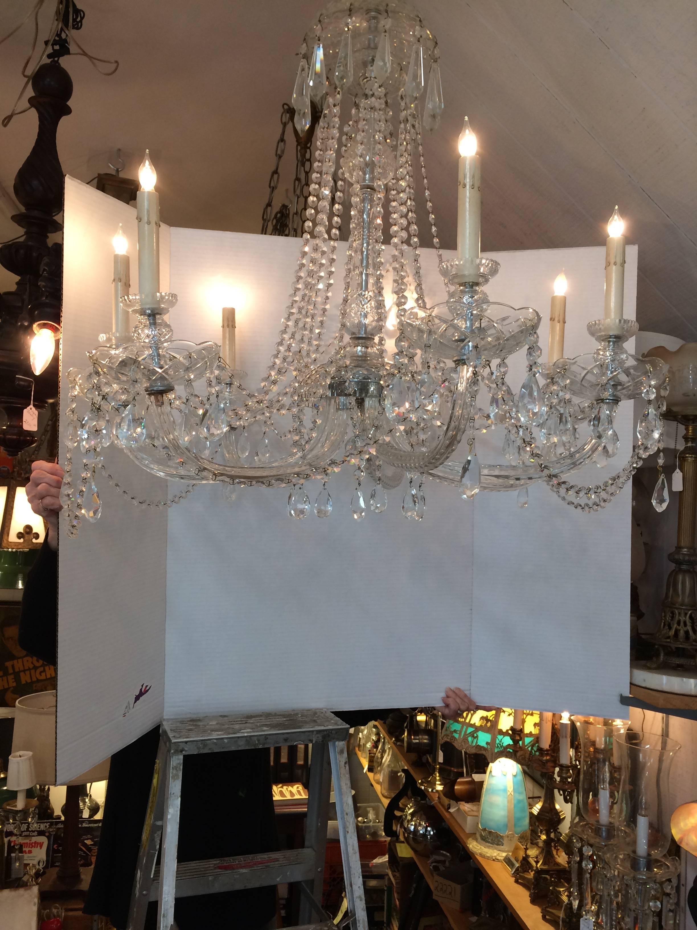 Radiantly glamorous very large French crystal chandelier having eight elegant cut crystal arms with teardrop embellishment, overall dripping cascades of crystal necklaces and a night sky of prisms, a crystal vase shaped center and inverted bobeche