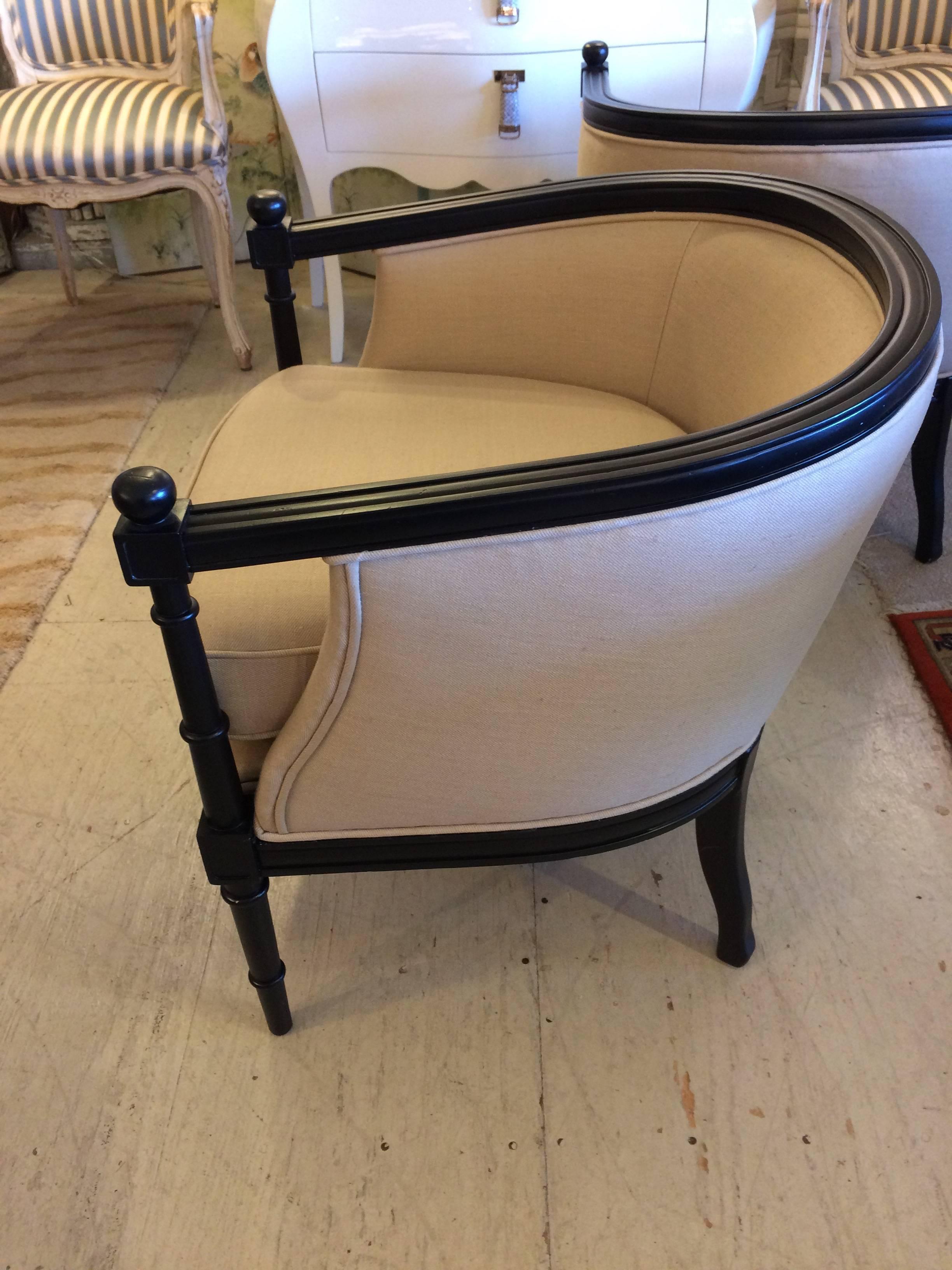 Two very sophisticated curvy barrel shaped tub chairs with newly ebonized frames and handsome neutral camel colored polished linen upholstery.