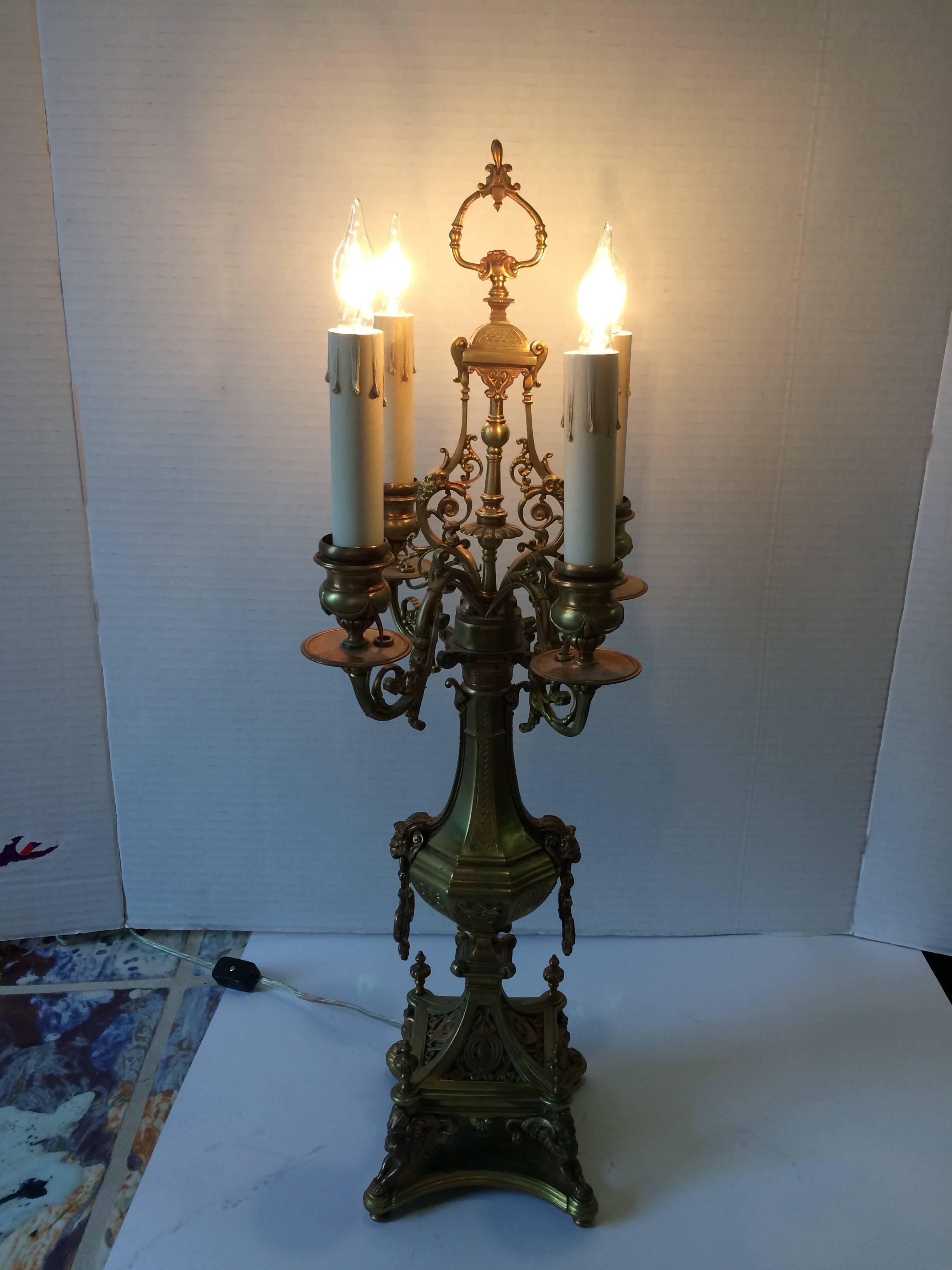 A rare supremely elegant pair of bronze candleabra lamps with ornate and artful details including lions heads and curlicues, 4 lights each and all original.