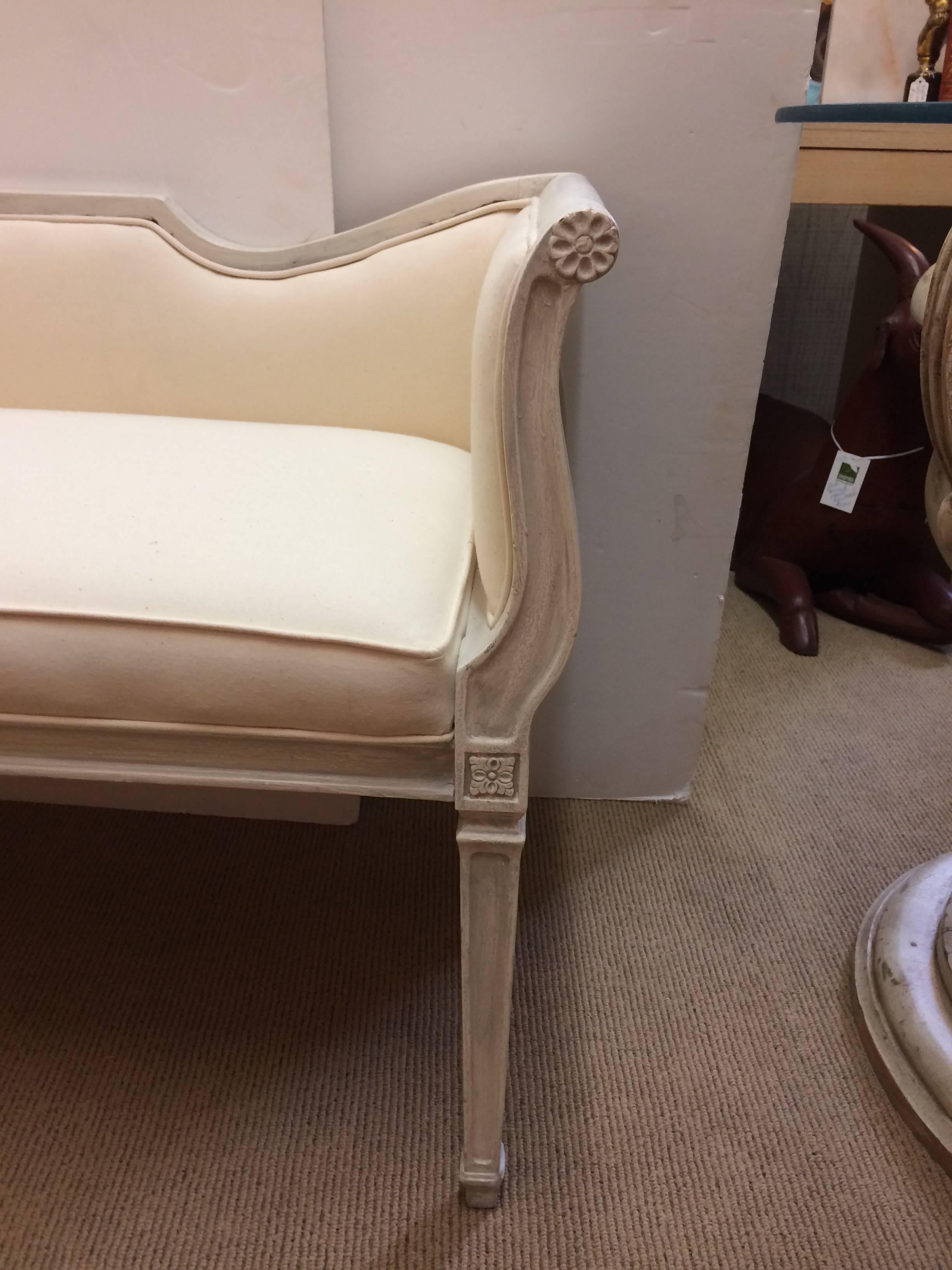 Very pretty French bench settee with a wonderful sensual silhouette and neoclassical style, having grey white paint and fresh white cotton duck upholstery. The back is 27 H, arms 28.