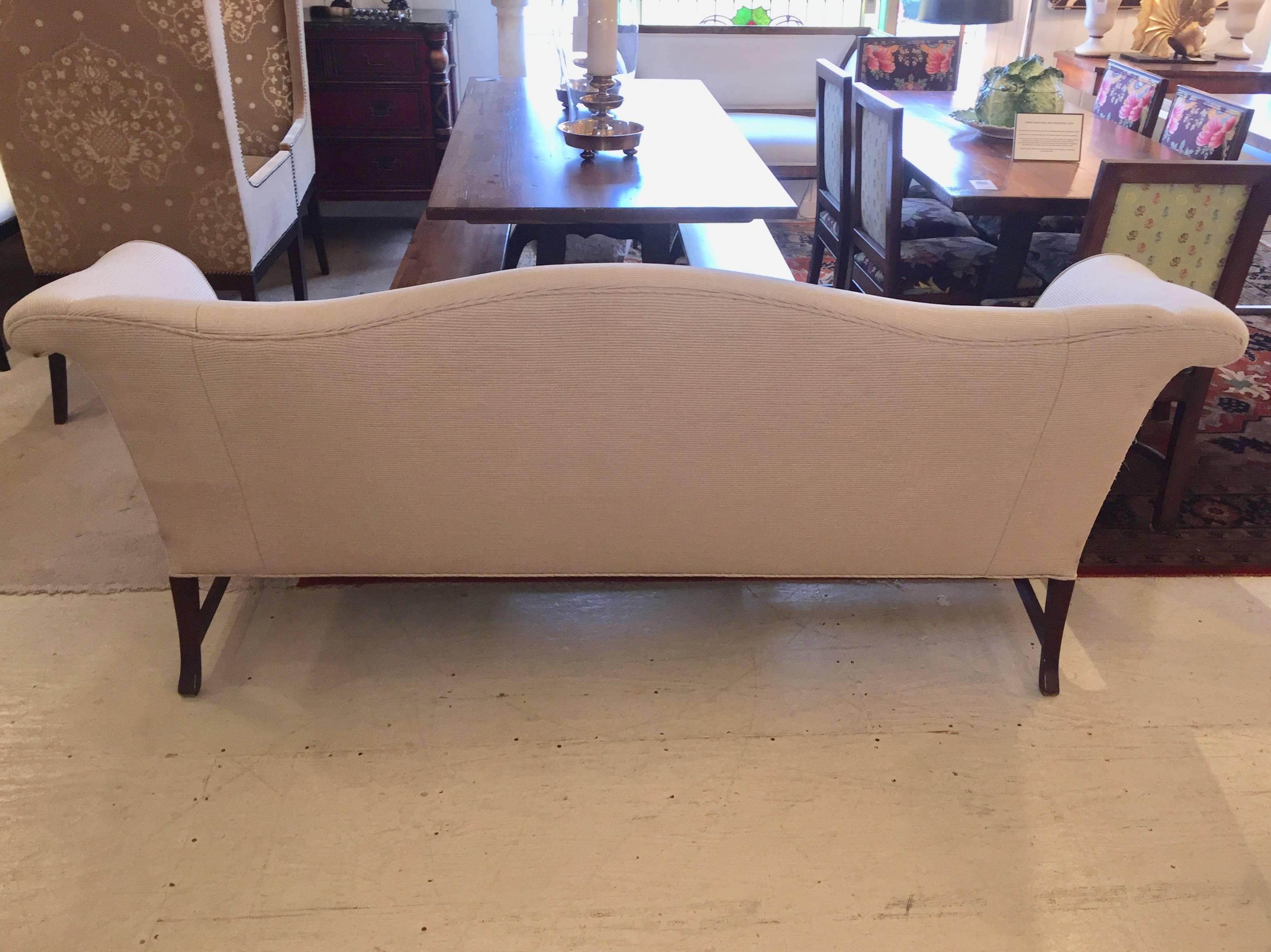 Wonderfully shaped classic camel back sofa having mahogany legs and stretcher, upholstered in a neutral taupe fabric. Back of sofa has some pulls, so best if it will be used against a wall or otherwise reupholstered.
Measures: Seat depth 19”.
