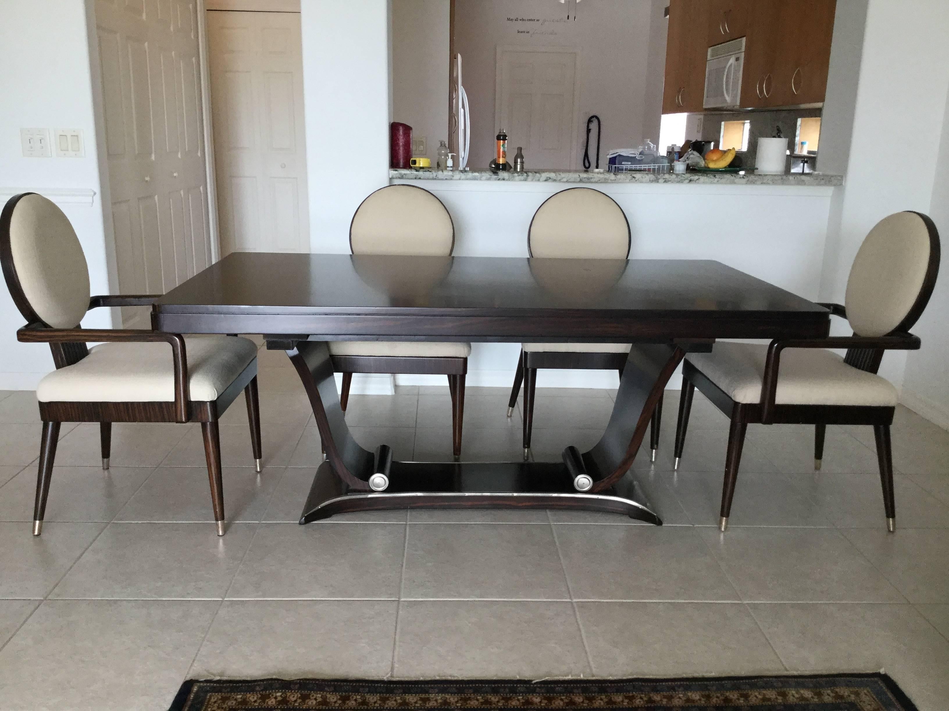 A magnificent modern rosewood dining table having a stylish curved pedestal base with two scroll shaped elements adorned with silver metal banding.
Six very chic matching chairs accompany the table, two arm, four side, having chic square seats