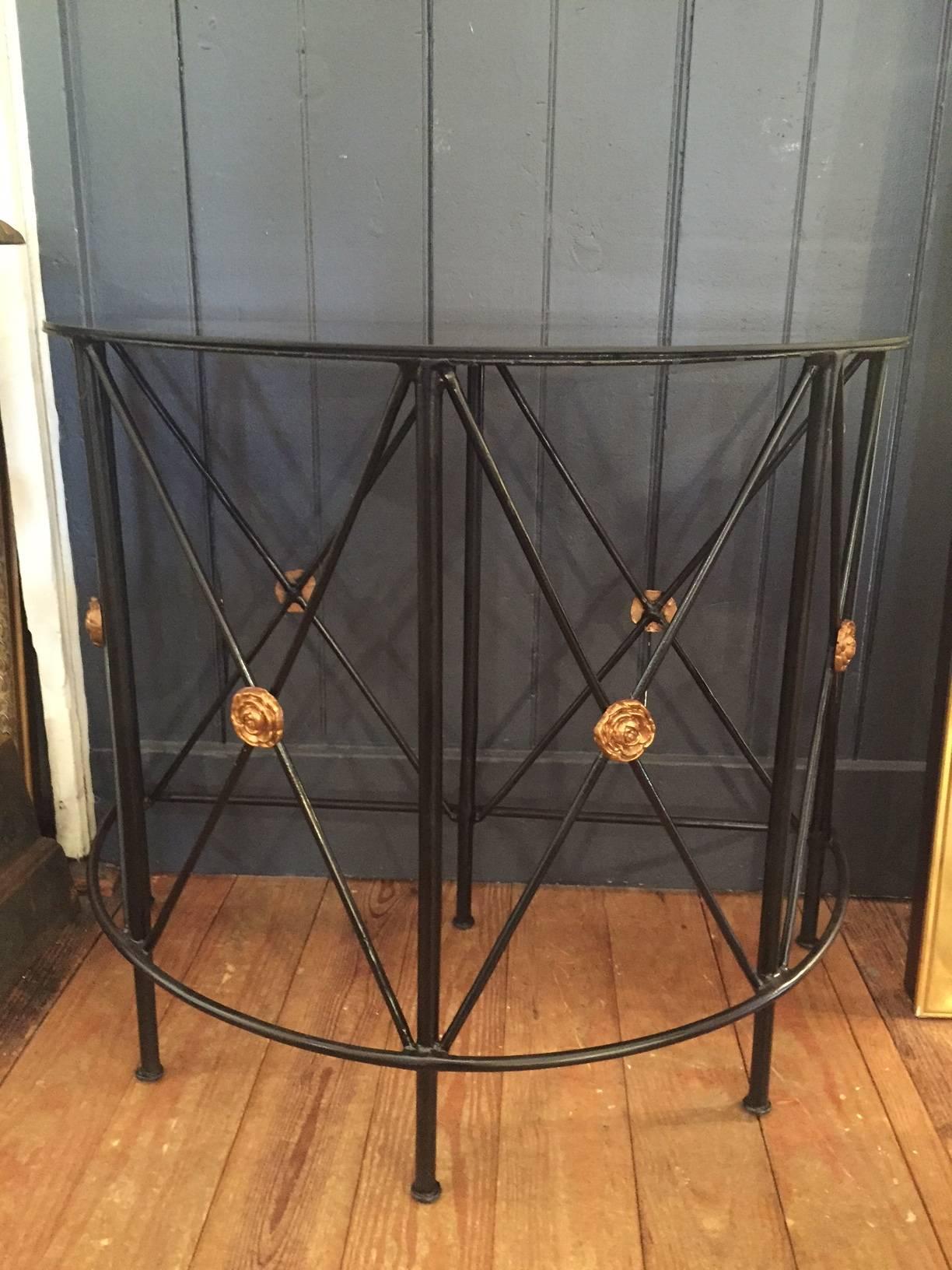 Stylish black metal neoclassical style demilune with black glass top and gold leaf florets.
Dimensions: 30.5" H X 35.5" L X $18.5" D.
 