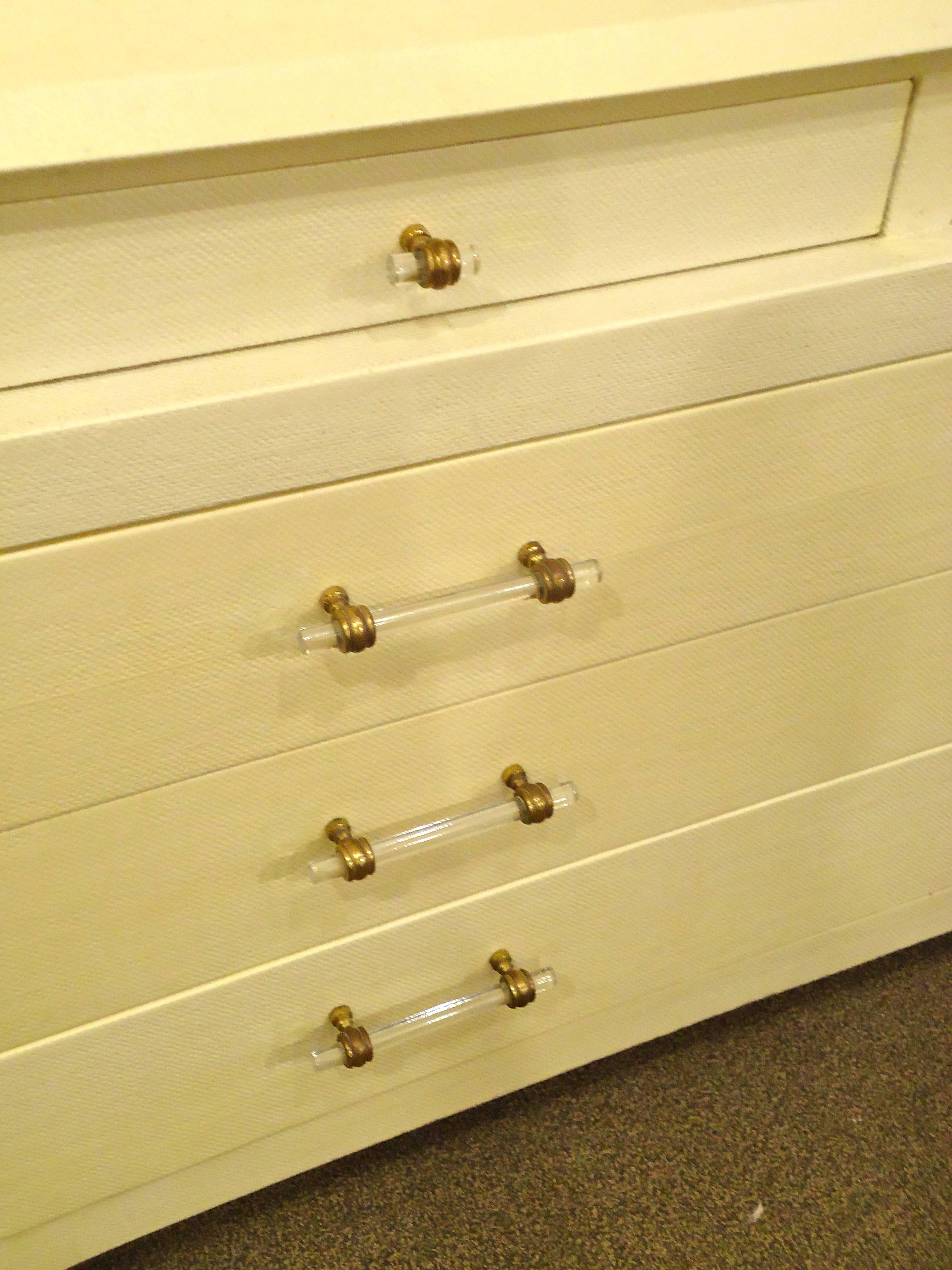 Smart and tailored stepped design having two narrower drawers on the top tier, three larger but still sleek drawers on the bottom. Wrapped in a cream colored linen and finished with cool Lucite and brass hardware.  Finished on the back too!