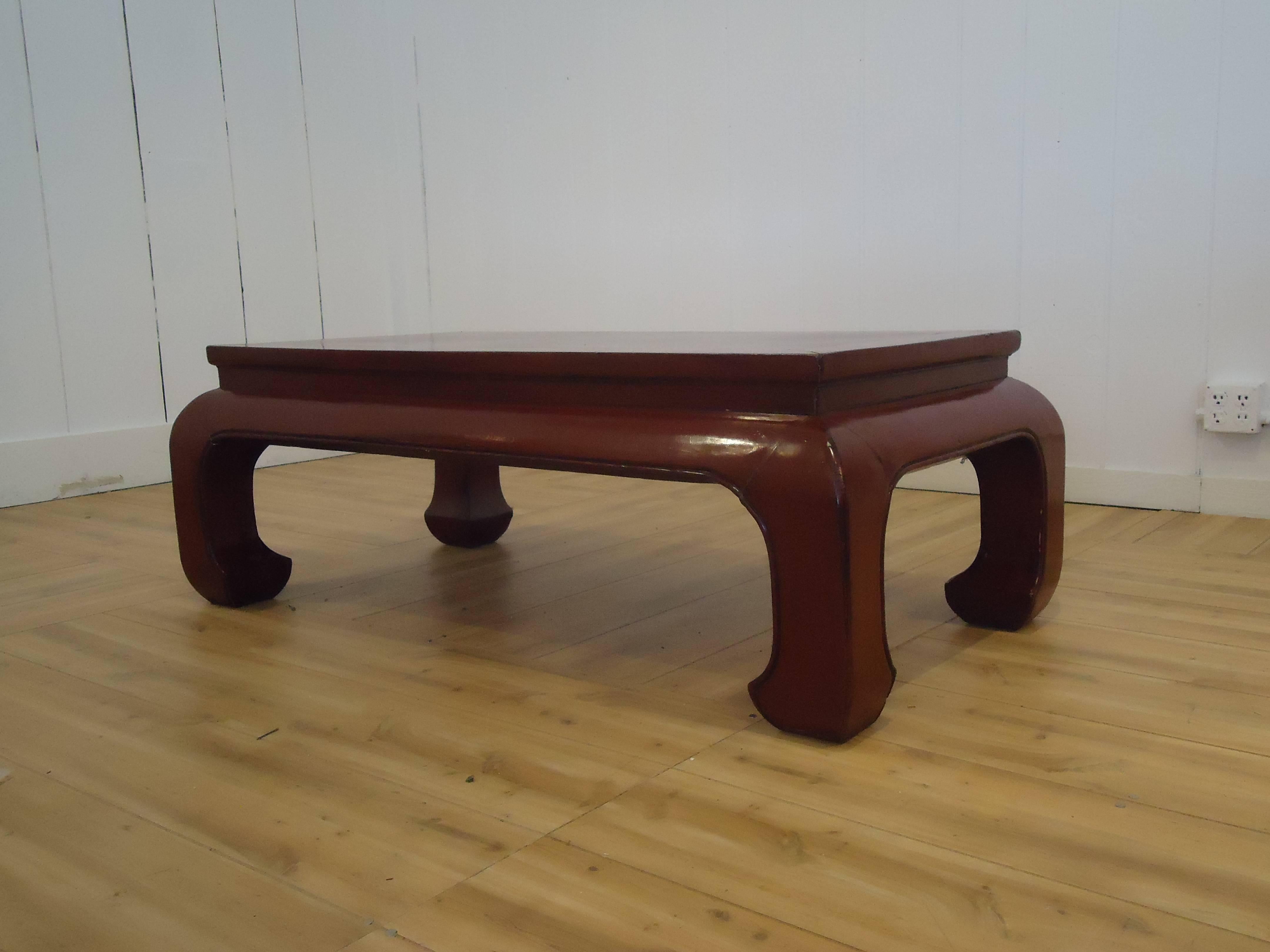 Solidly constructed antique wooden coffee table painted a rich dark reddish maroon, with handsome curved legs.