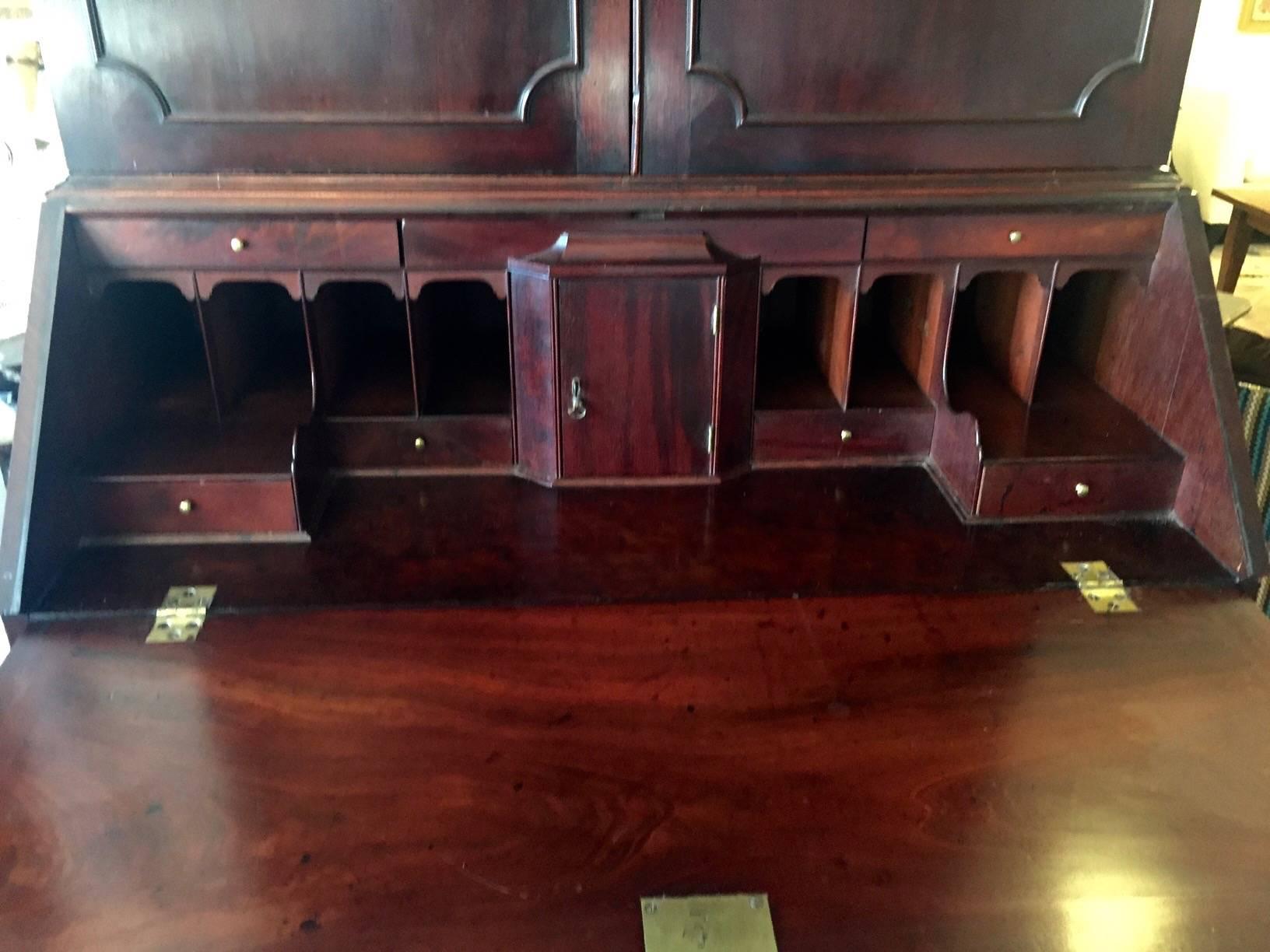 Stately Georgian solid mahogany blind door secretary having multiple adjustable shelves, full interior desk with lots of cubbies, and four drawers beneath, resting on straight bracket feet. Original hardware. Measures: 42 W base 43 W top
Desk