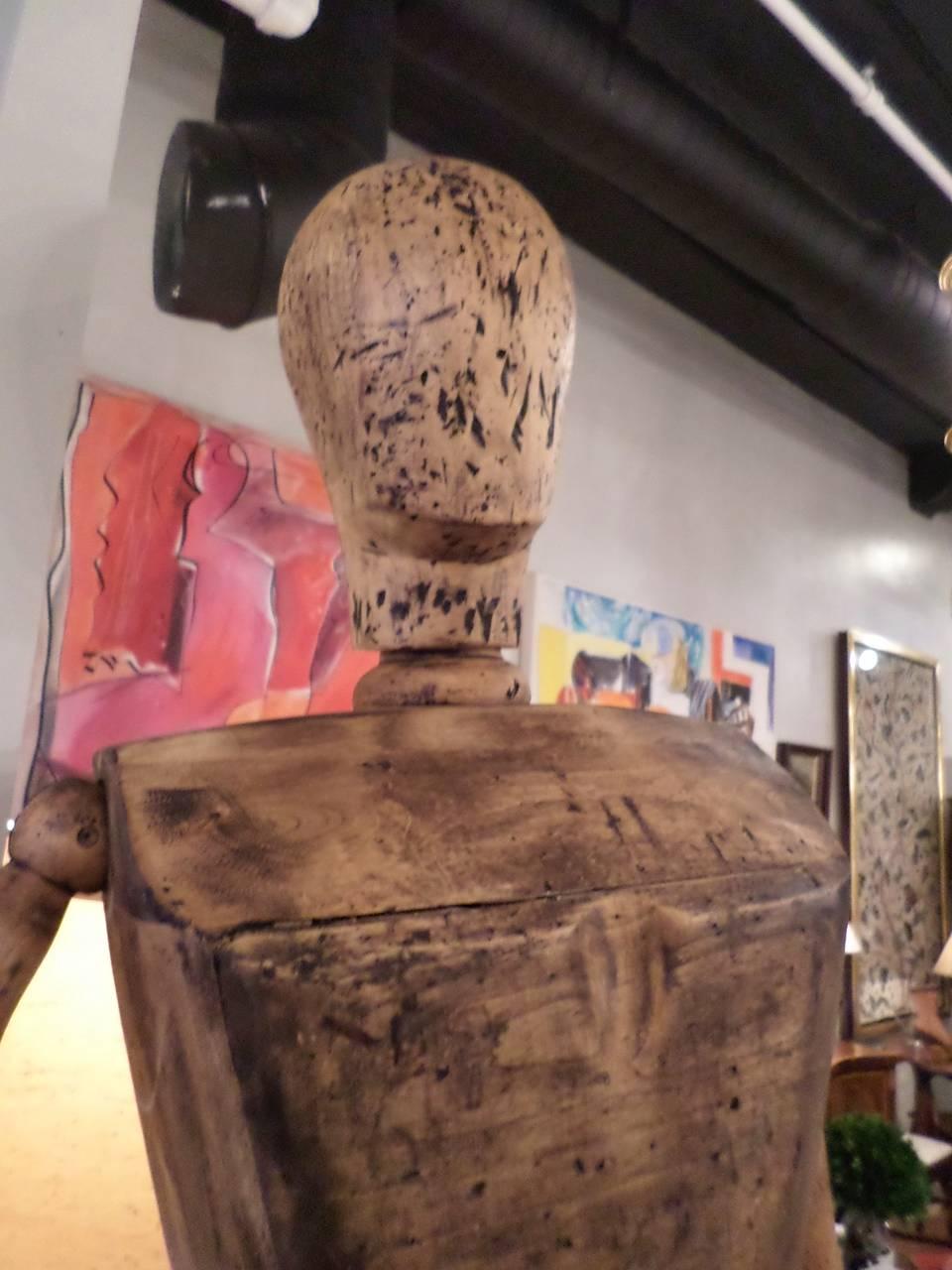 Life-sized fully articulated artist’s mannequin, with an adjustable iron armature attached on the back, resting on a triangular Stand. Distressed patina added.
 Base is 33 wide x 27 deep;
74