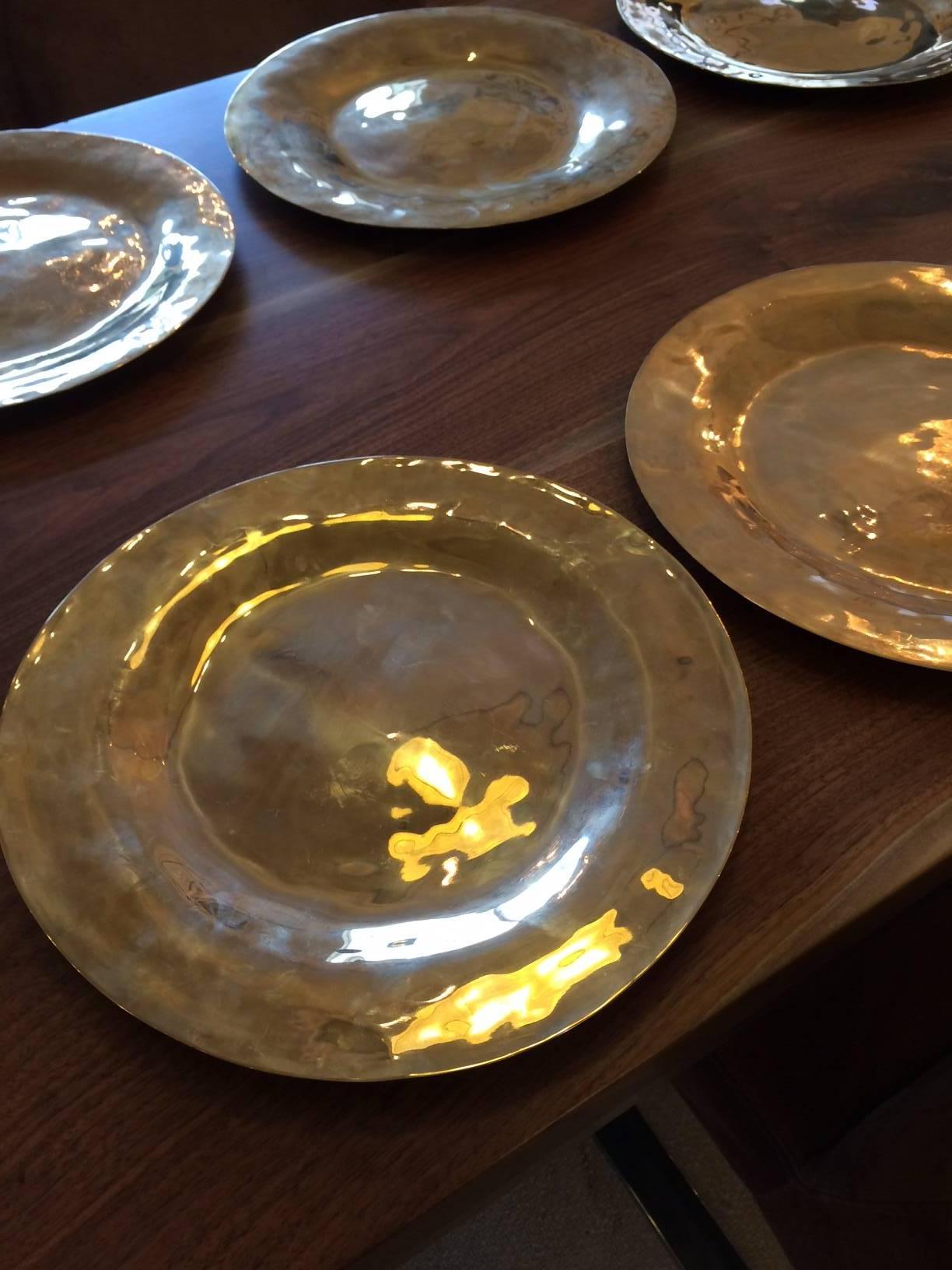 Warm golden brass charger plates, hand-hammered and richly lustrous, made in Italy.