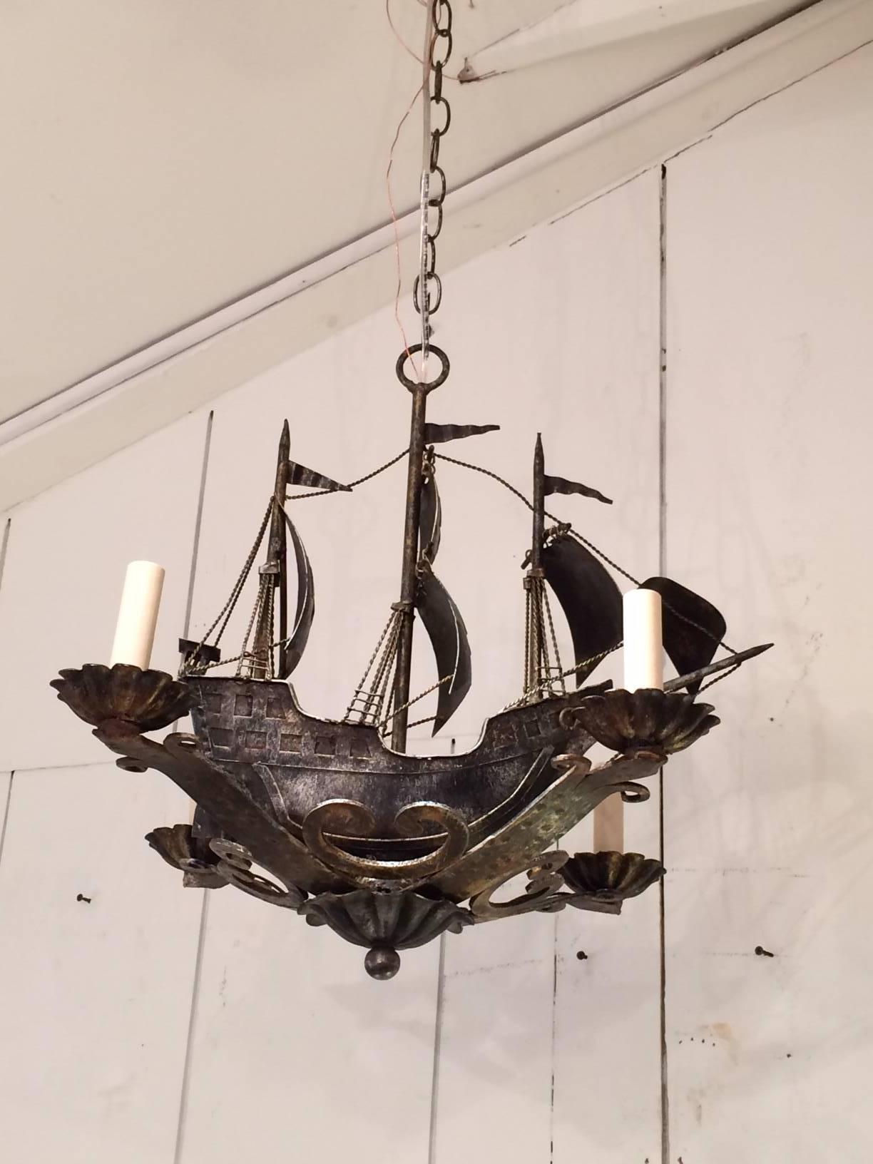 Rare pair of handmade light fixtures that are sensational old world sailing ships constructed with greyish silver aged iron, meticulous details including anchor, flags and sails. Functional chandeliers with four arms, 60 watts each and newly rewired.