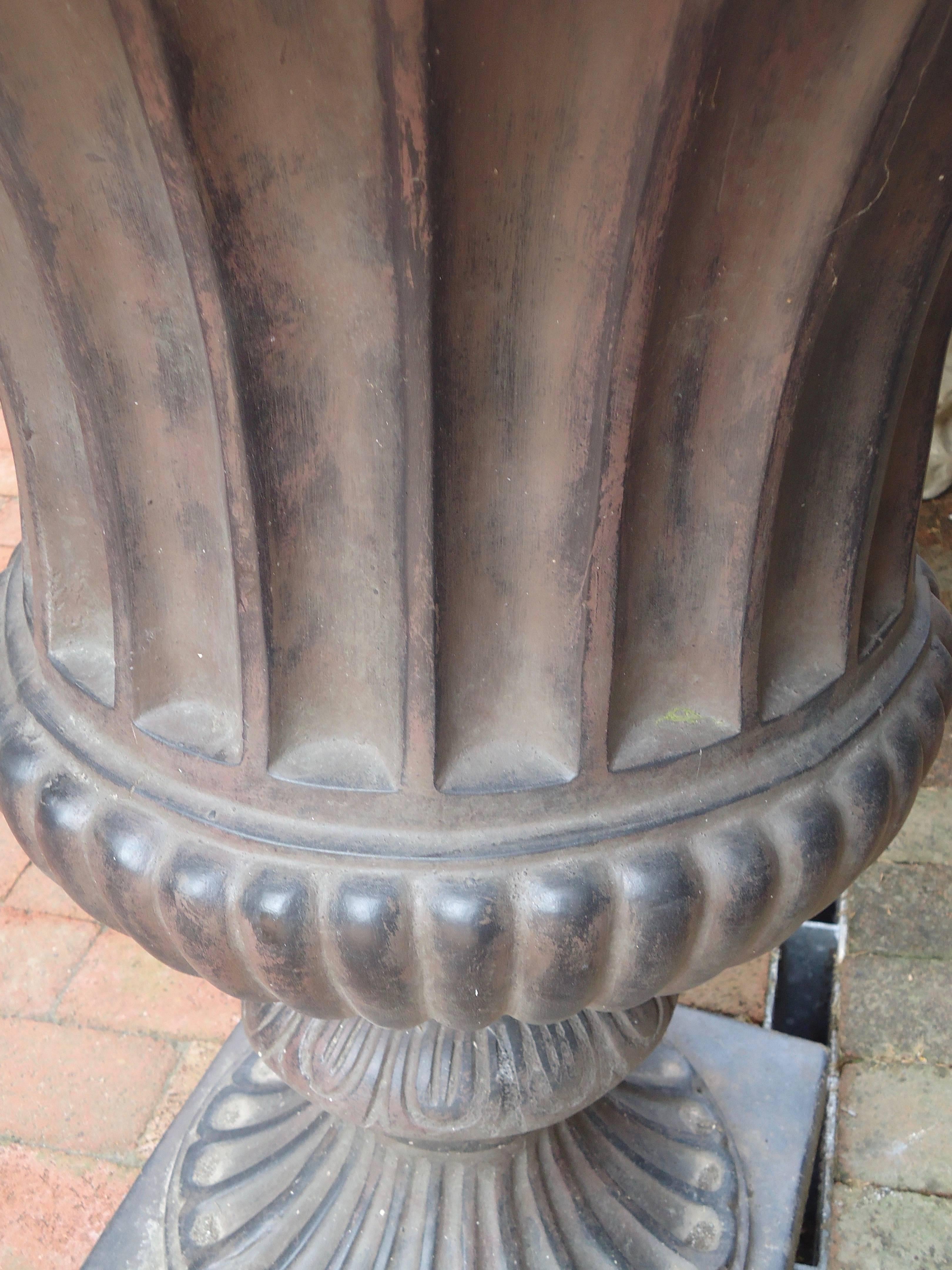 A gorgeous Classic fluted urn in fiberglass resin, hand cast from the original antique urn, having intricate details and a hand-painted faux aged black iron finish. This high quality medium is impervious to weather, durable and maintenance free.