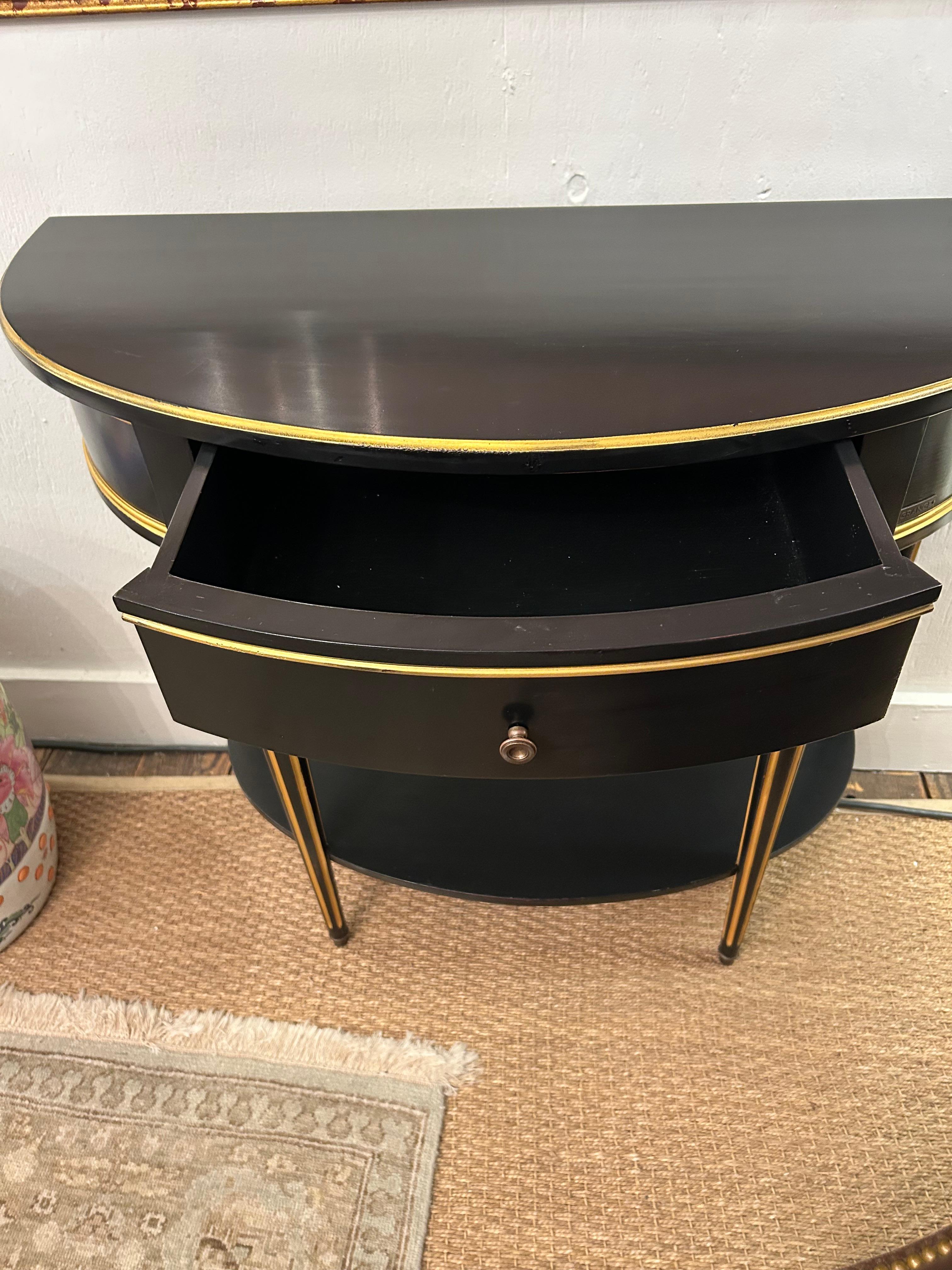Stunning small Demi lune console table, ebonized with gold detailing and single drawer.  Legs are reeded and tapered and there’s a lower shelf.