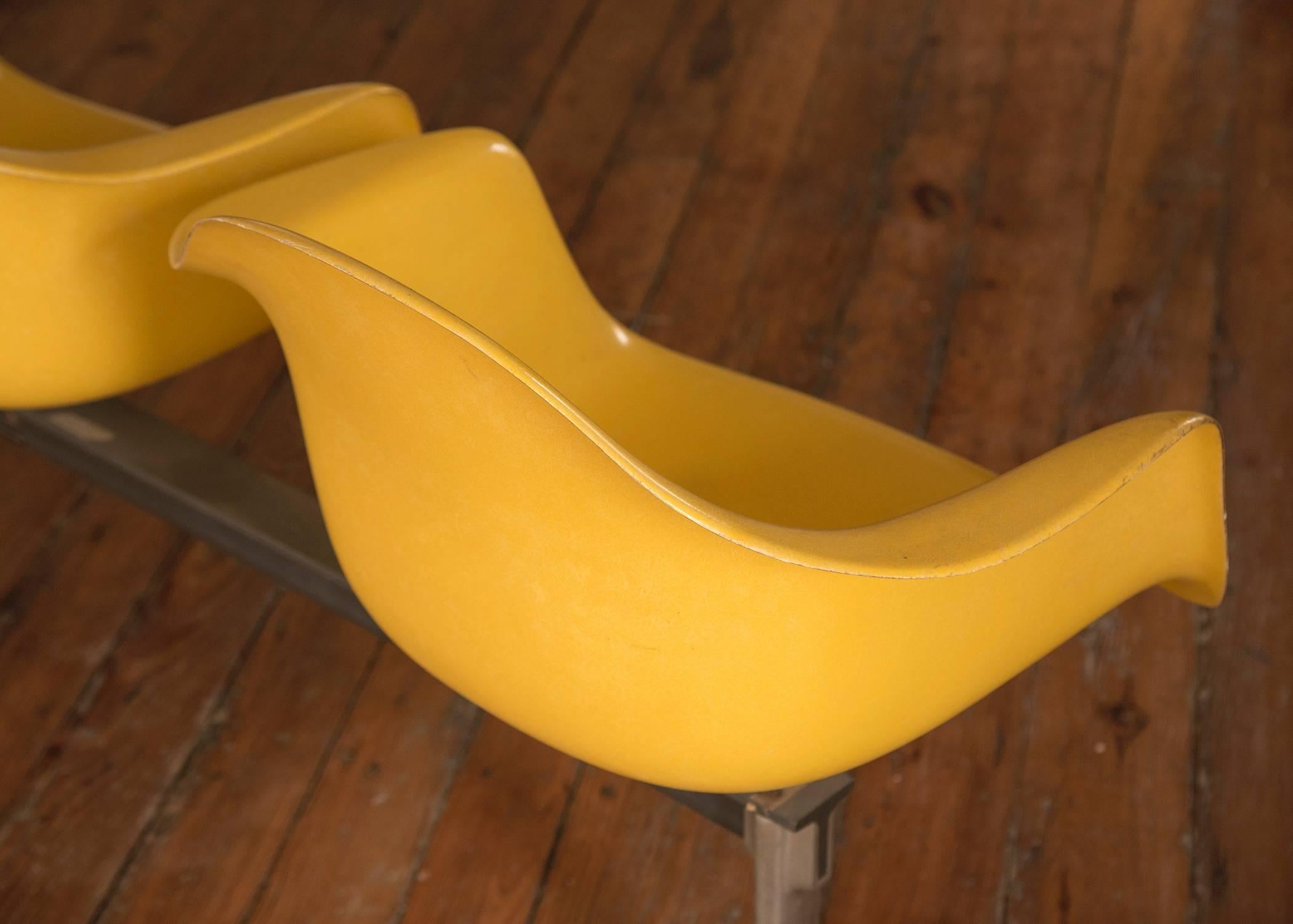 Vintage tandem seating by Eames for Herman Miller, the seating has three fiberglass seats in sunny yellow with a chromed and black metal base.
Seat height 18