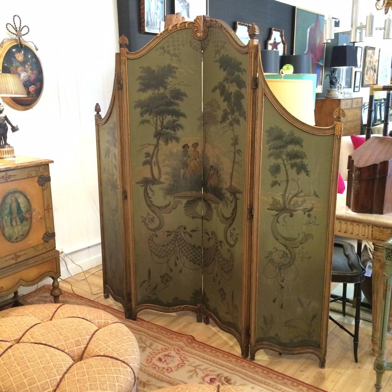A rare gem of a French hand-painted and giltwood screen, having four accordion panels in a muted green with pastoral scenes on the front, and wonderful chintz upholstery with double welting on the back. In addition to use as a screen or room