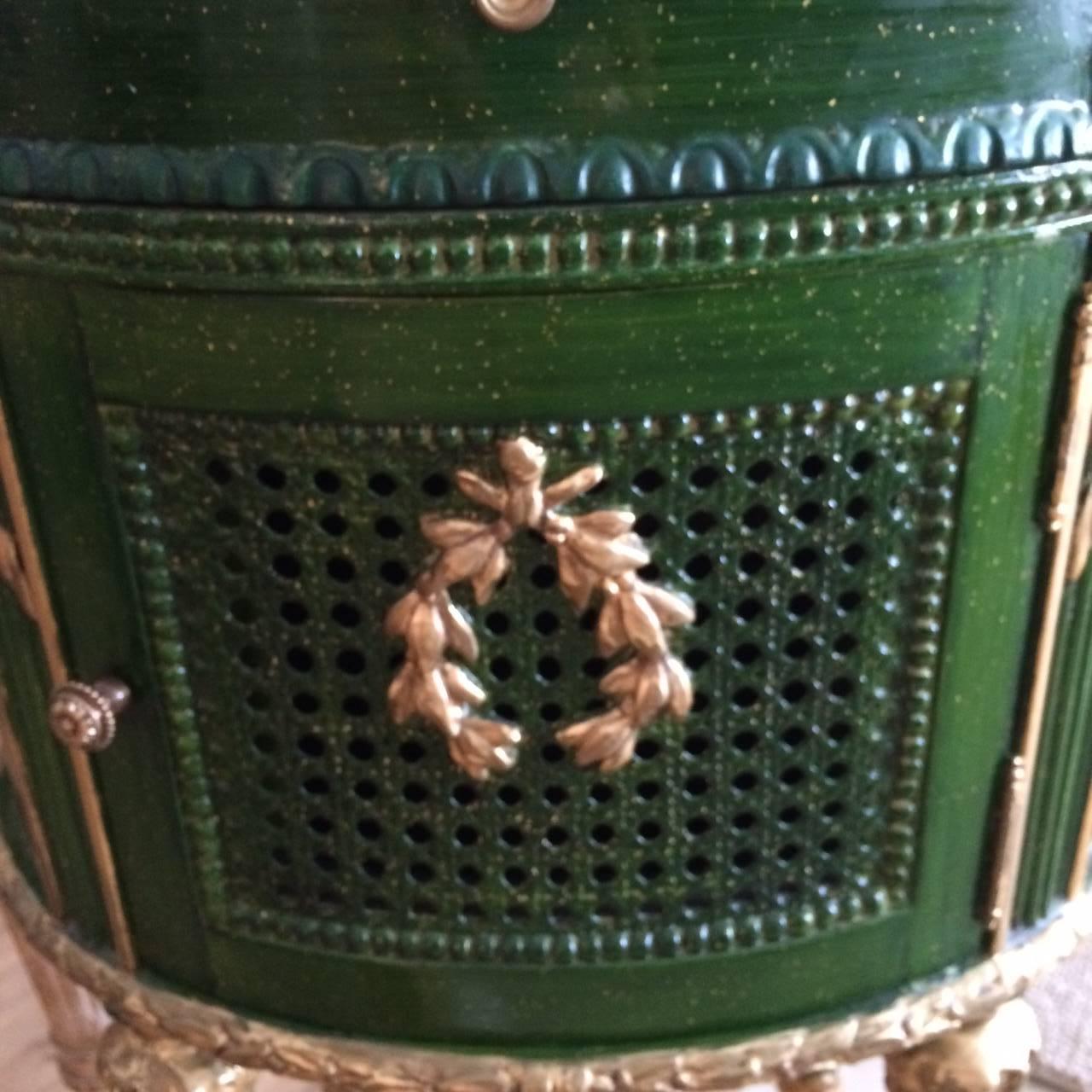 Darling oval French Louis XVI style side table or nightstand having a black and cream faux marble-top and a wonderful emerald green color with gold leaf accents.