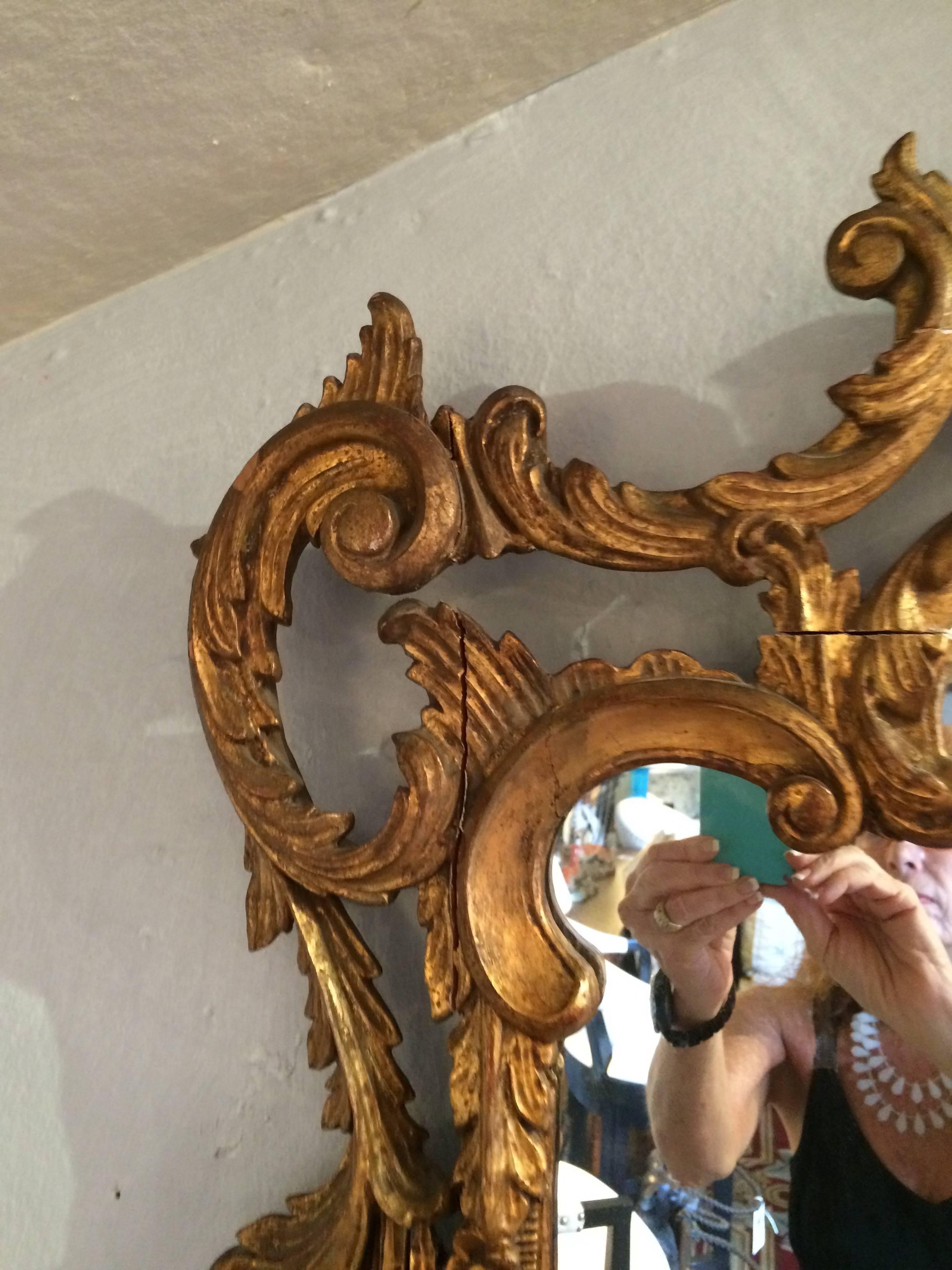 Glamorous antique giltwood rectangular mirror with ornate carved wood designs.