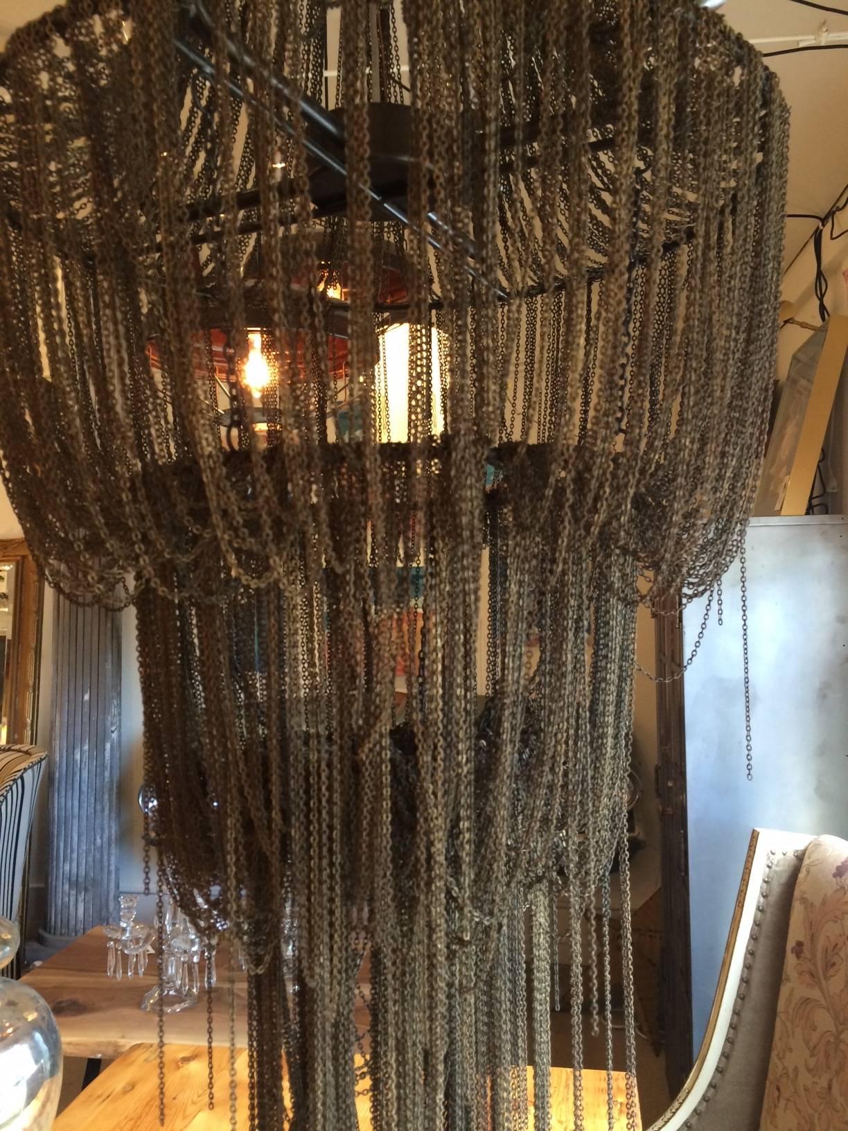 Dripping with drama, the Arteriors yale chandelier has dramatic swags of cascading iron chain draped into tiers with staggered lengths creating a tassel-like effect. A few loose wisps of chain produce a slightly disheveled, deconstructed look that