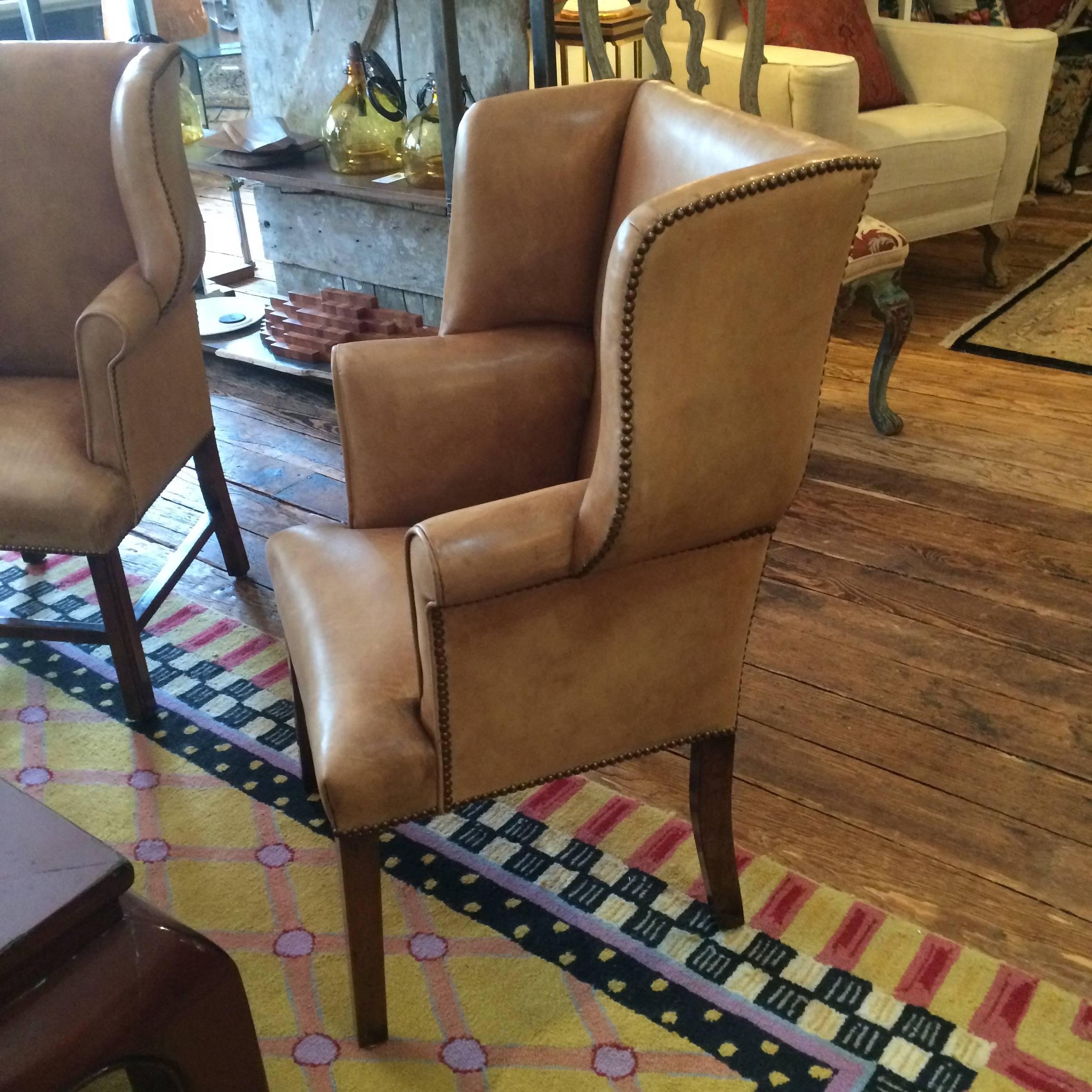 Wonderful Chippendale style distressed leather wing chairs in a fabulous apartment size. Leather is a light tannish brown with age appropriate wear including some minor scratches and discoloration as shown in photos. Rich in character and patina.