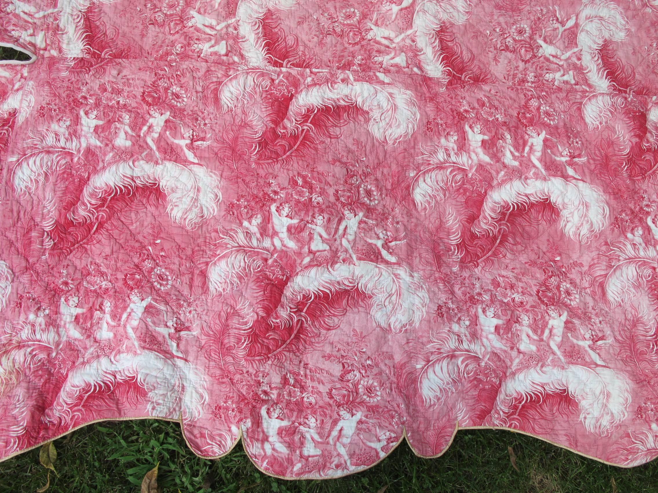 Charming antique quilted toile bed cover in lovely shades of pink and cream, circa 1860, that has been made to fit a twin sized daybed. The bucolic scene depicts cupids frolicking in gardens with feathers and flowers. 

 