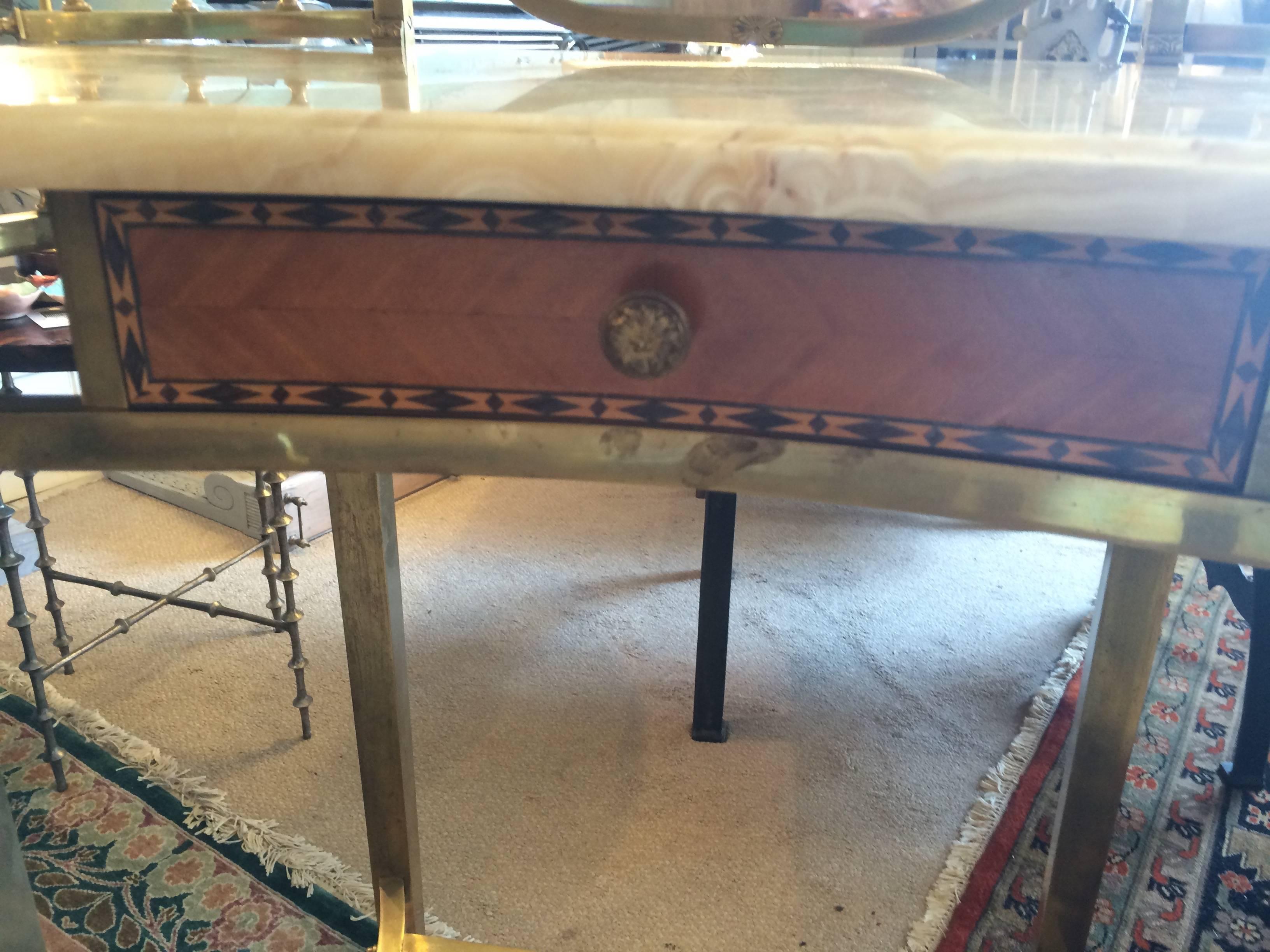 Very unusual vintage vanity having lovely kidney shaped cream marble surface, with solid heavy brass gallery on top and bottom, pretty blonde wood and inlaid drawer, bevelled mirror and decorative brass flourishes. Height to marble surface 31.25