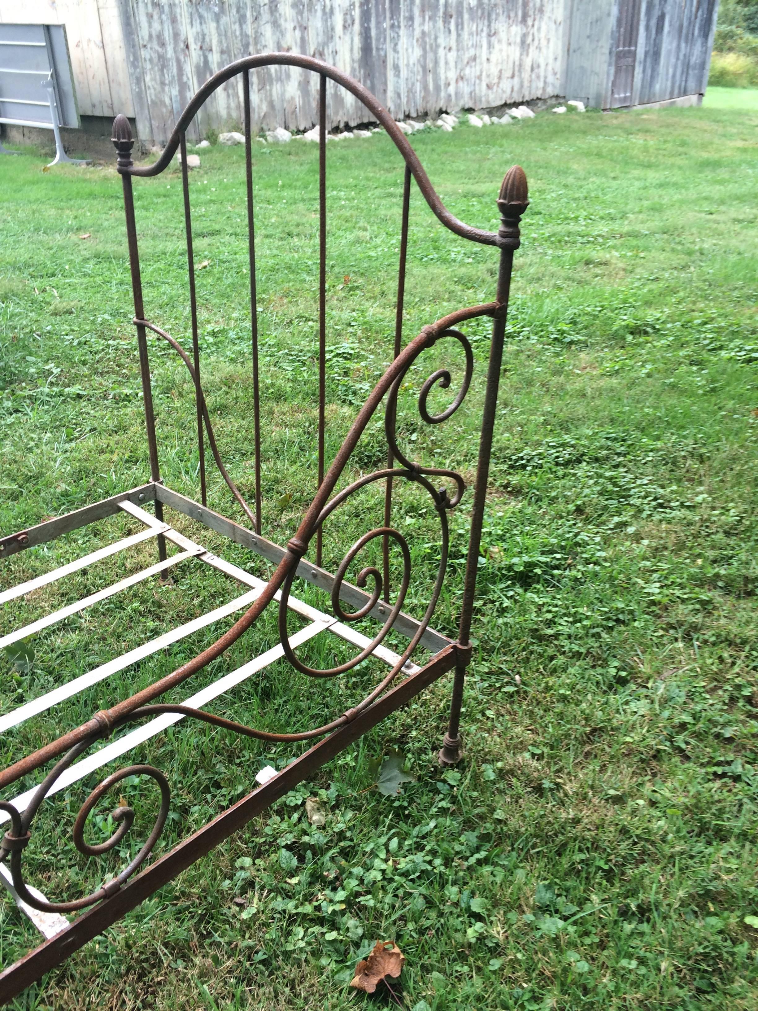 Classic French iron daybed with a natural brown patina, curlicues and acorn finials, on casters. Ends fold in, Campaign style. No mattress included.