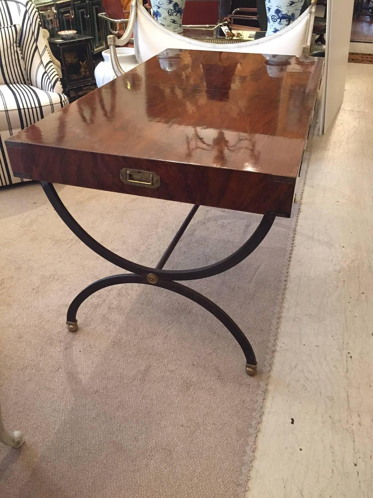 Sleek handsome glossy walnut writing desk, two drawers and inset brass handles in the Classic Campaign style. The base is an airy yet solid black iron and brass stretcher with brass medallions and gilded ball feet. Drawers are lined with Italian