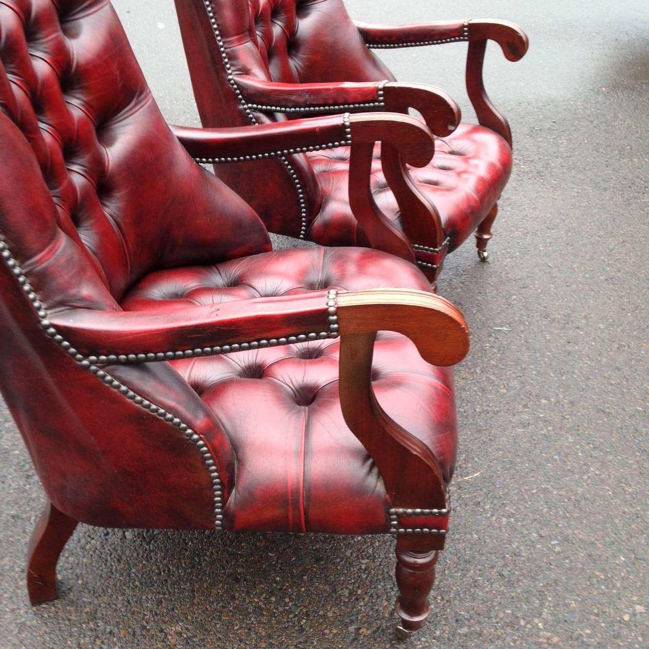 Pair of William IV mahogany and tufted red leather library chairs, circa 1850 with sloping backs, open Curule arms and turned front legs ending in casters. Fine patina and slight color difference on the arms due to wear. 
 Seat height: 14” 22”