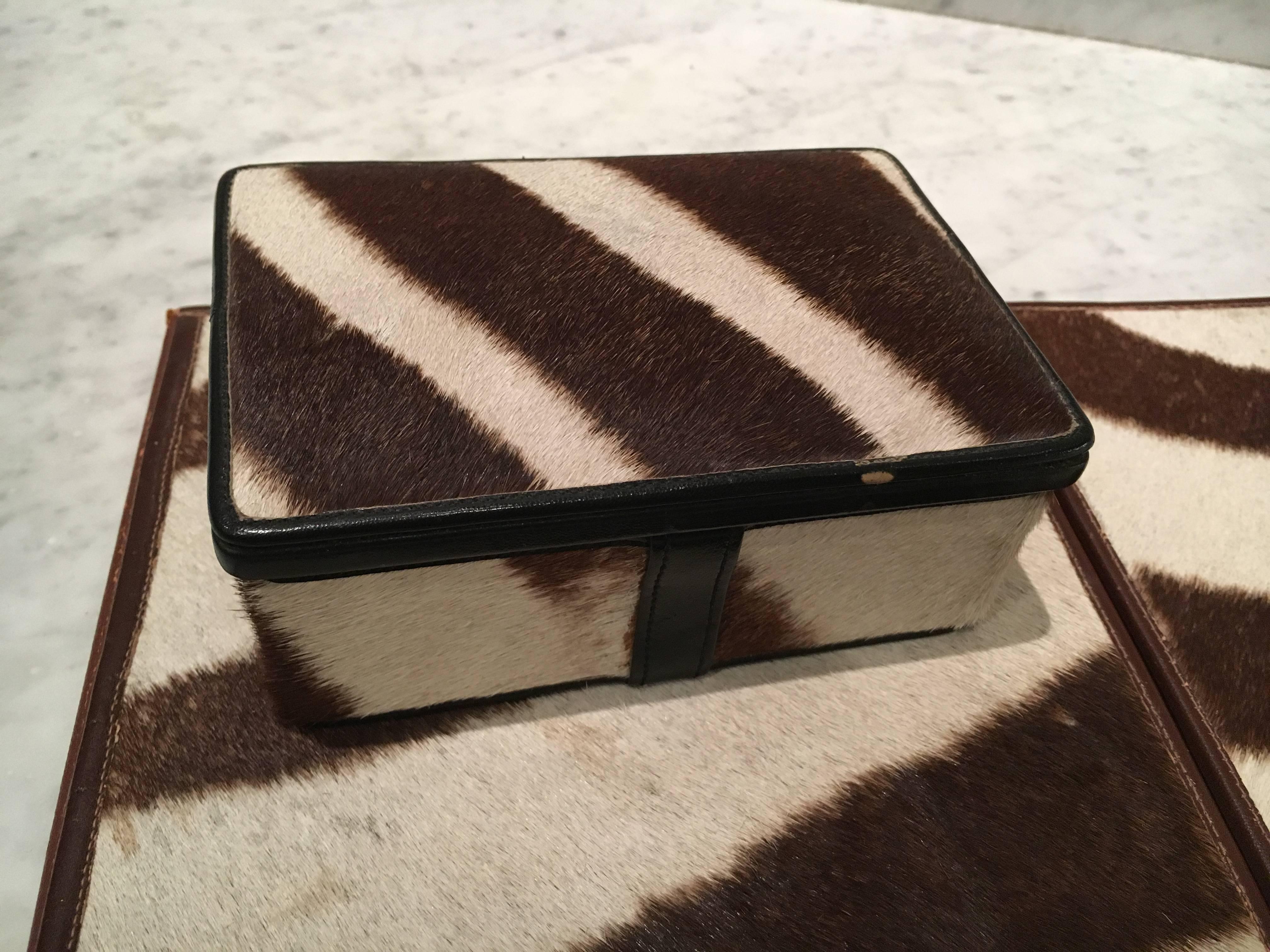 Rarely found desk set in authentic vintage zebra hide and leather, including a desk blotter and box. Blotter measures 11.5" deep X 18" wide when closed and 11.5" deep X 36" wide when open. The box measures 6.25" wide X