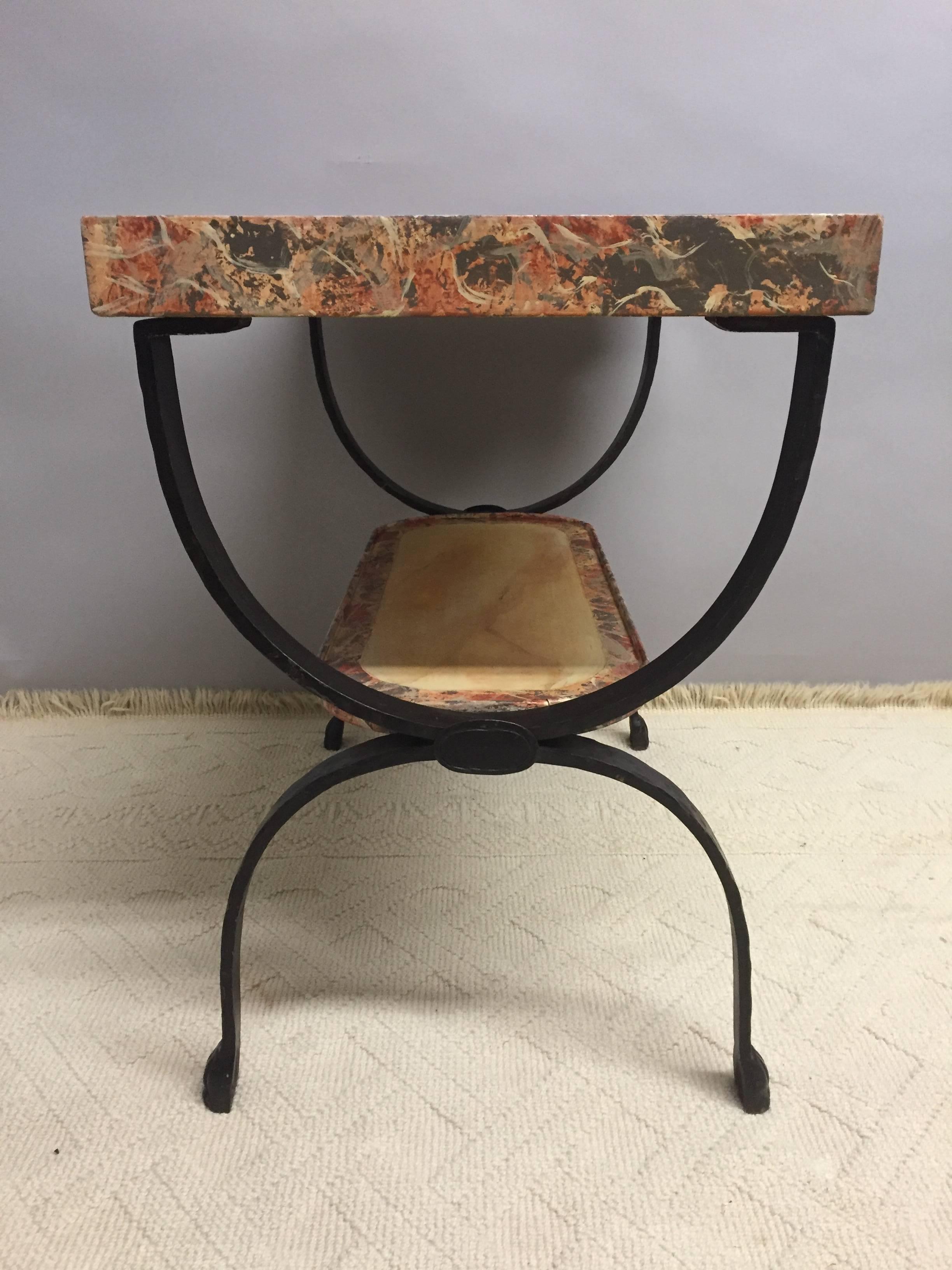 Handsome one of a kind end table having two tiers of hand-painted faux marbleized surfaces with a central cream rectangle, outlined in rouge, cream and grey. U shaped black wrought iron legs.
 