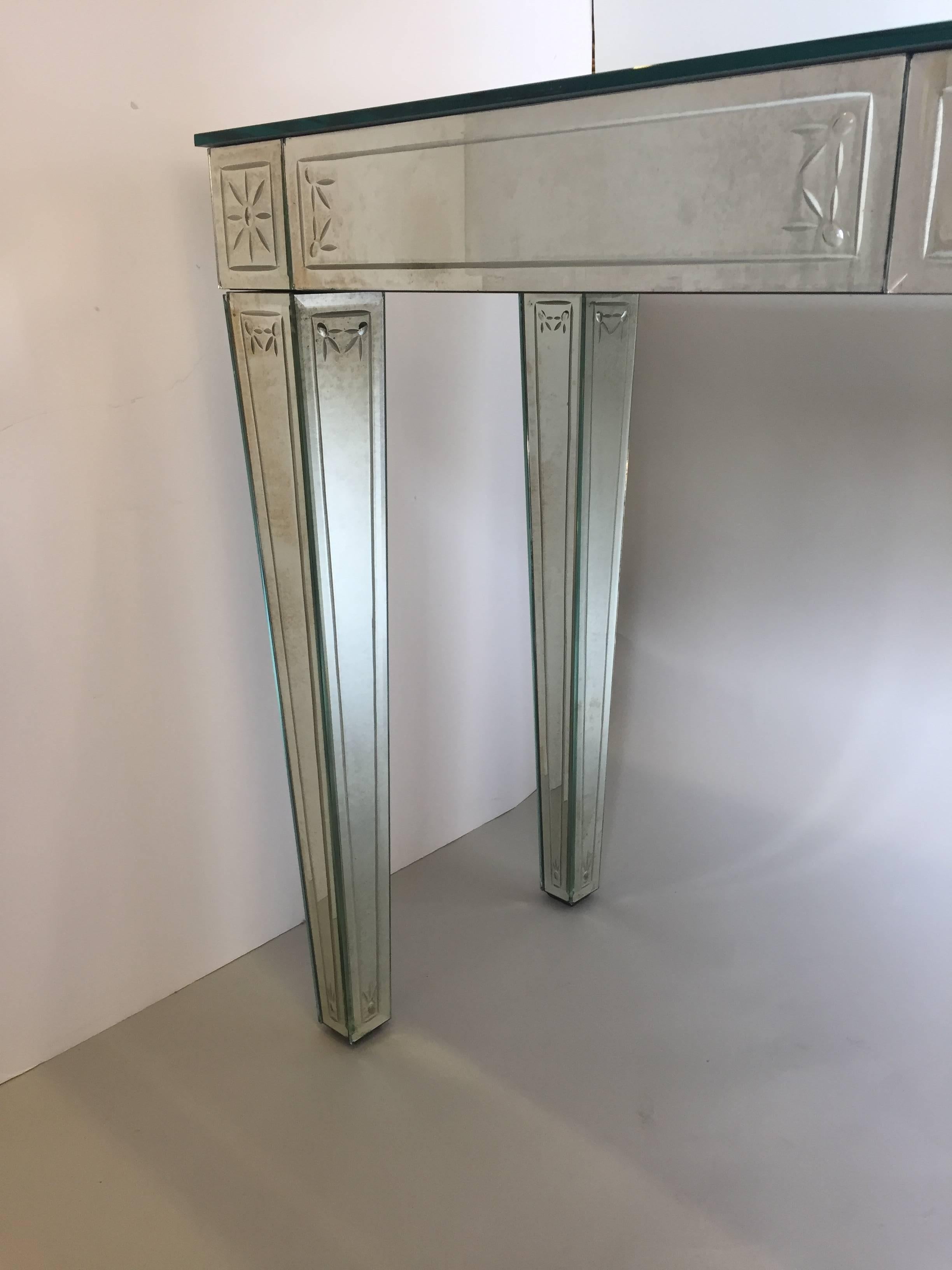 Glamorous bevelled aged mirror console having elegant etched decoration in a neoclassical style.