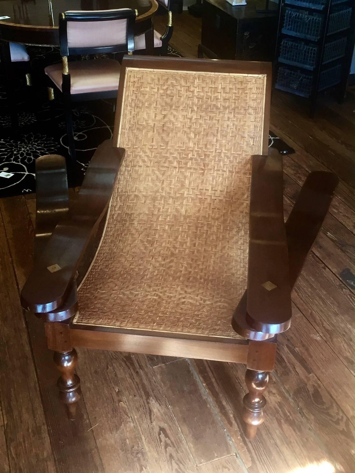 Anglo-Indian plantation chair with original caned seat and turned legs. Exotic wood frame with brass screws and decorative square which anchor the screw mechanism for the arms to extend. The extended arms aided in comfort for the owner to prop up