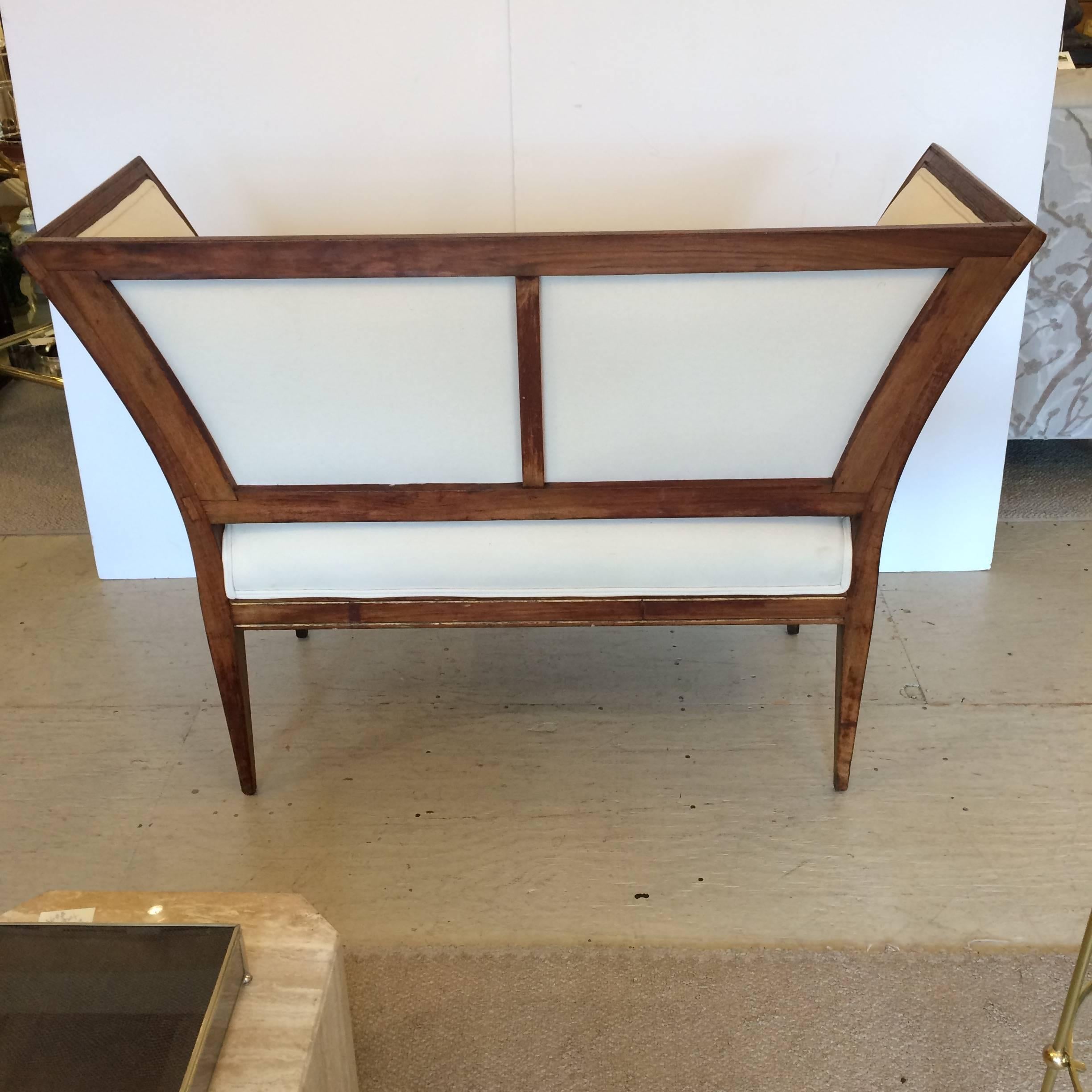 Wonderfully angular fruitwood loveseat with subtle decorative gilding and carving, with windowpane back and freshly upholstered in heavy gauge white duck.