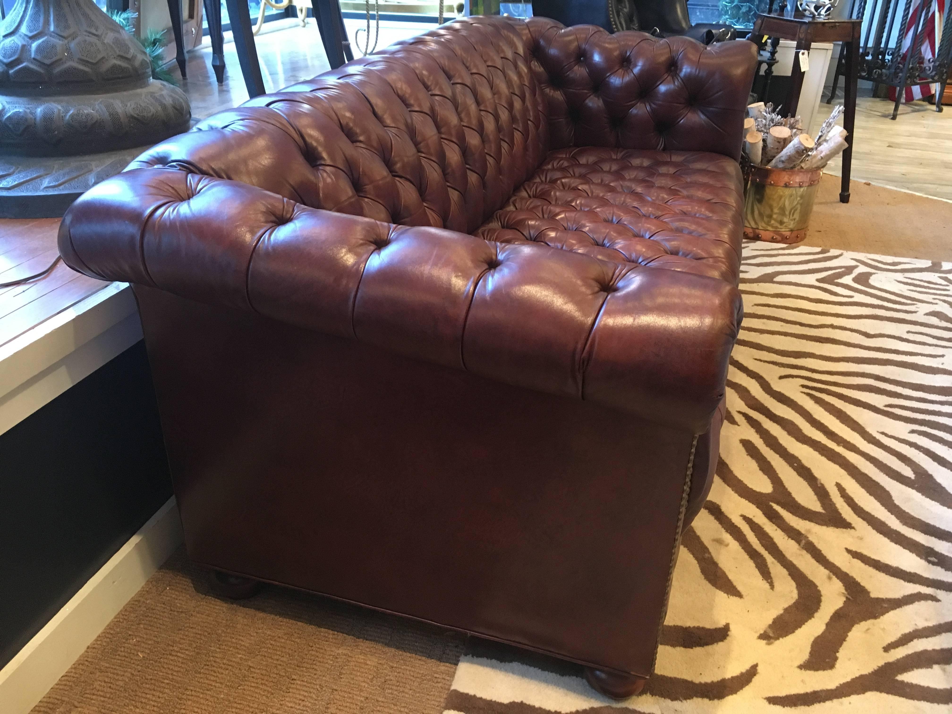 Vintage tufted top quality cigar brown leather Chesterfield sofa with scroll arms, wooden bun feet and handsome brass nailheads. Comfortable, traditional and classic style.