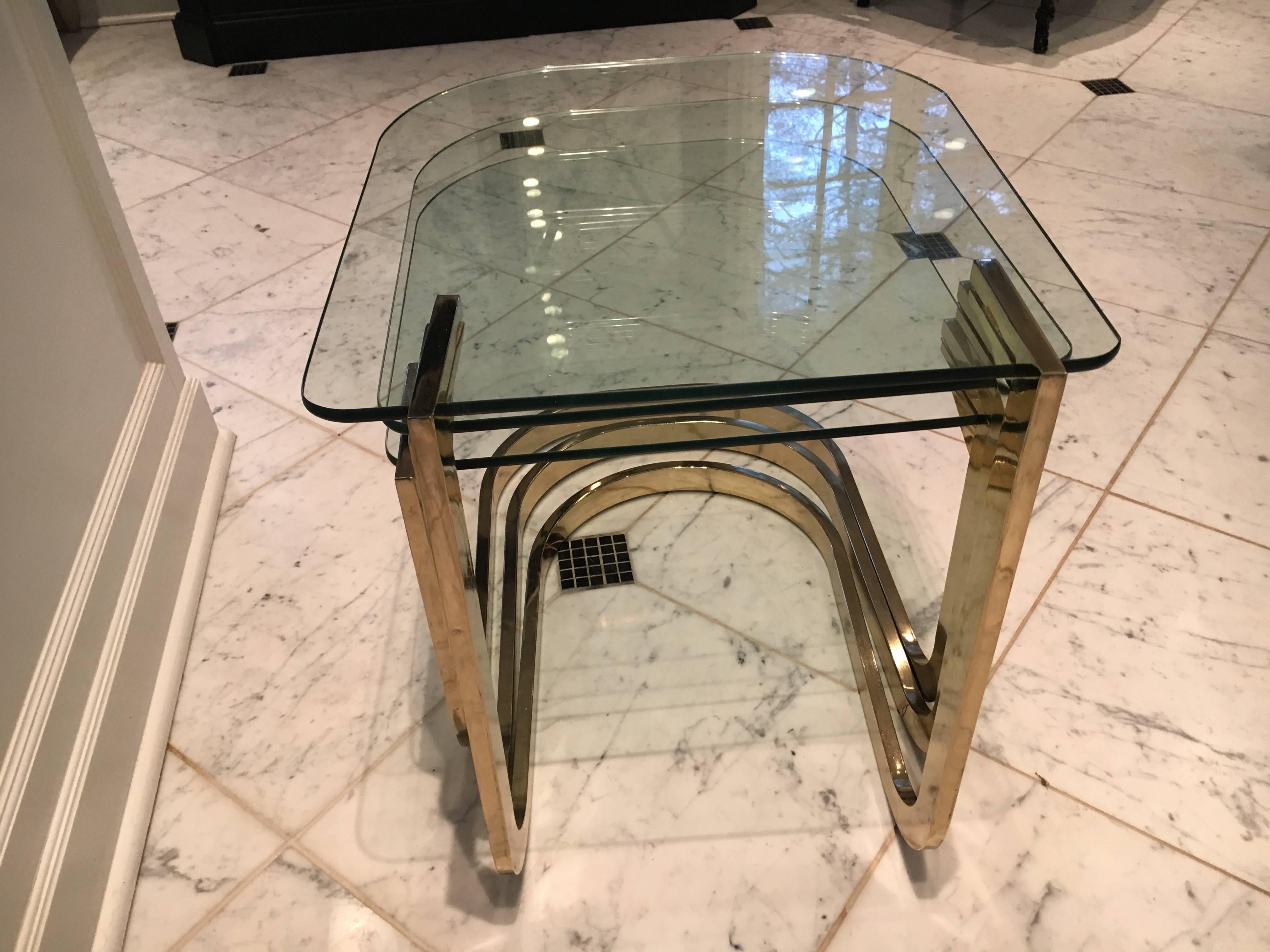 Set of three nesting tables by Milo Baughman for Design Institute of America. Handsome and versatile, these brass and glass tables add Mid-Century modern pizazz anywhere. Brass is in perfect condition with no pitting. The bottom two tables are in