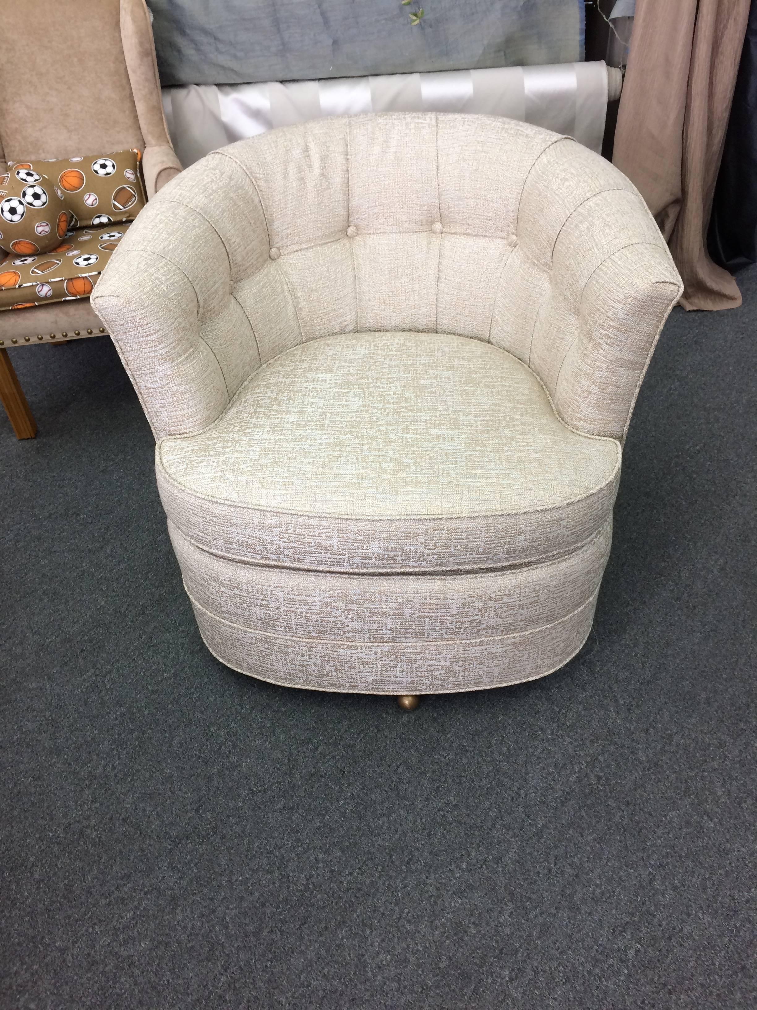 Two comfortable medium sized sexy swivel chairs from the 1960s having tufted backs and brass ball feet, that swivel easily 360 degrees. Fresh from the upholsterer in a retro style textured tone on tone weave, off-white.