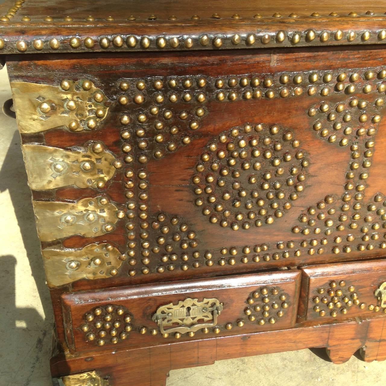 Anglo-Indian dowry chest, circa 1850, made of a heavy walnut-like wood and dovetailed construction, the overhanging hinged top with brass tack trim opening to a well, the till on the left hiding a secret compartment; the front with three drawers.