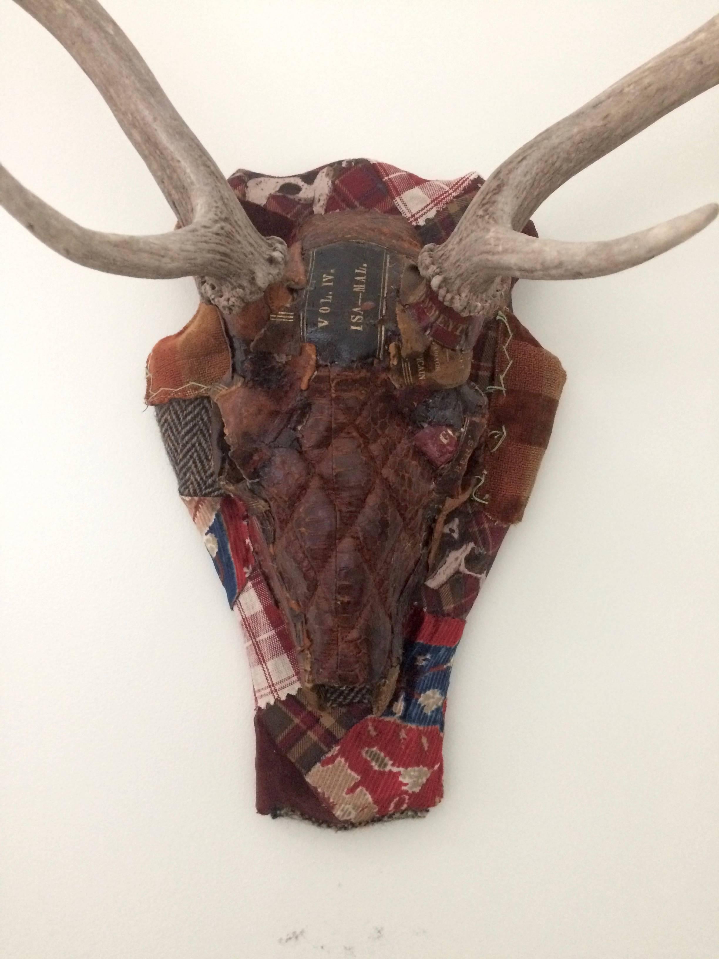 Richly layered mixed media skull sculpture using an imaginative array of textural elements including vestiges from a vintage quilted leather handbag, bits and pieces of leather books, Ralph Lauren plaids and cordoroy and cuttings from an old crazy