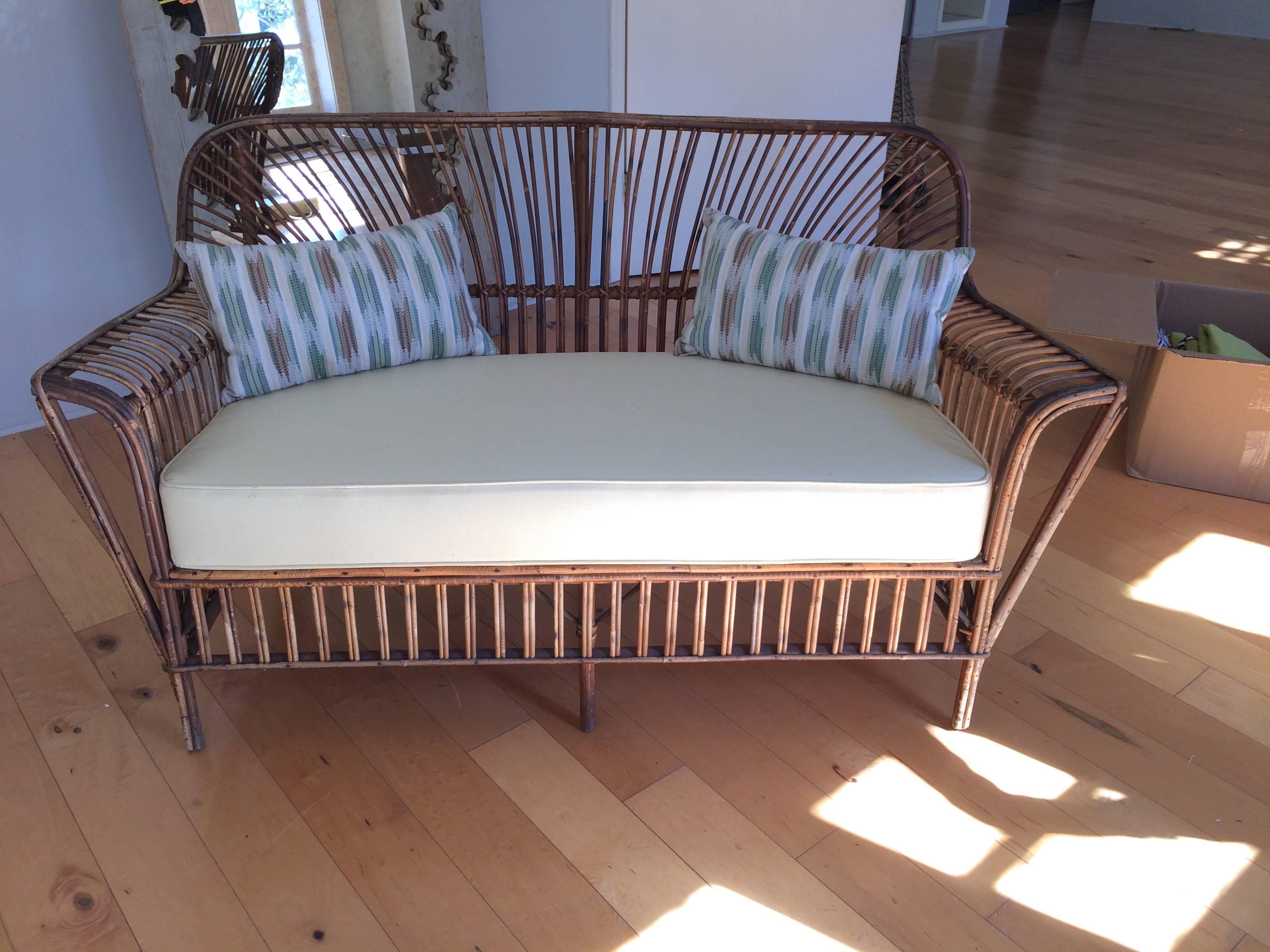 Classic rattan loveseat with lovely curved arms and custom off-white seat cushion and two pillows included. Beautiful front and back. Great for a covered porch or indoors. Seat 18" H 21" D.
