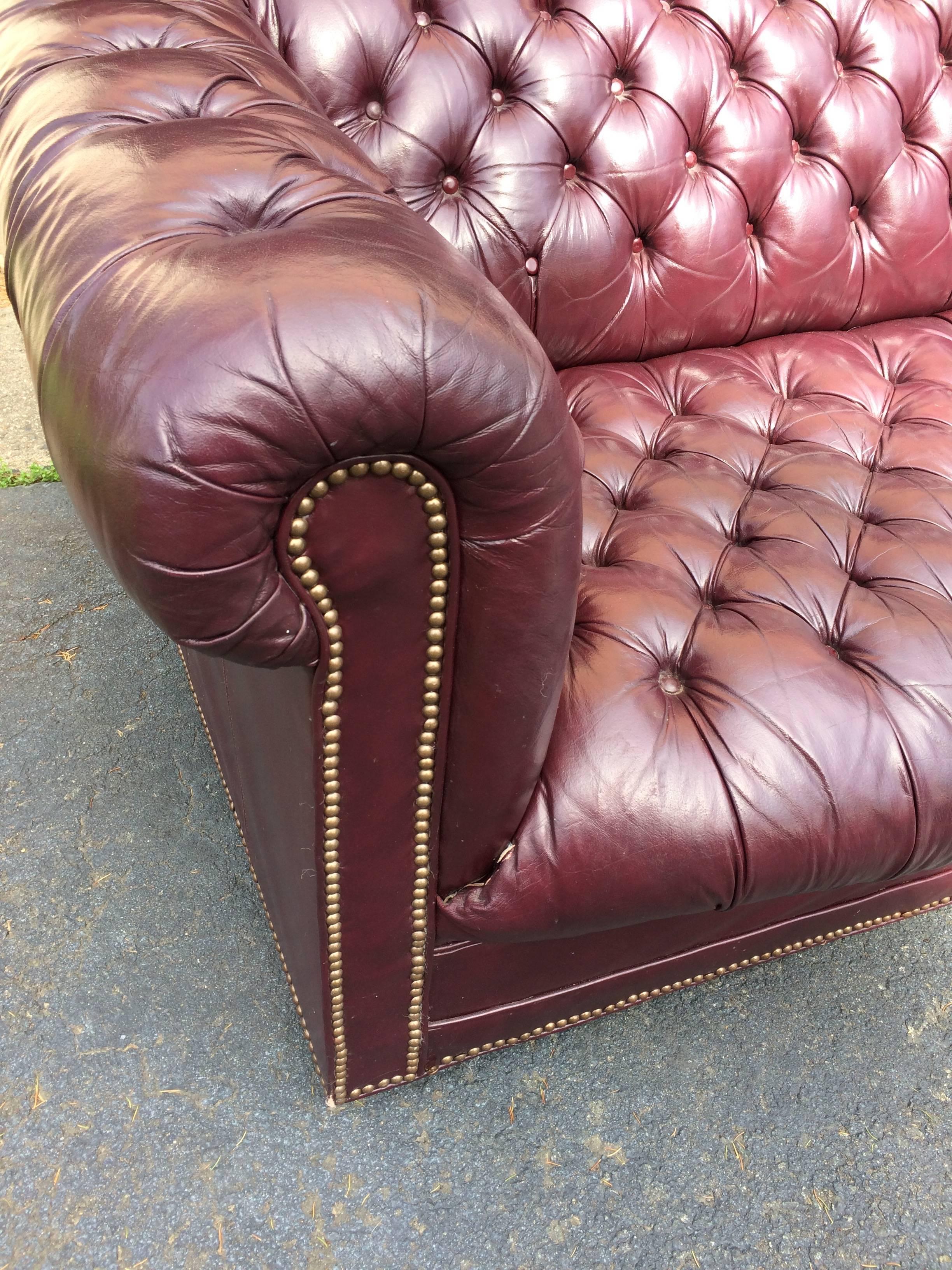 Wonderful Classic Chesterfield sofa in a dark purple eggplant color finished with brass nailheads. Some age appropriate wear, such as a bit of loose leather at the front corners and one or two missing nailheads.  Seat depth 27