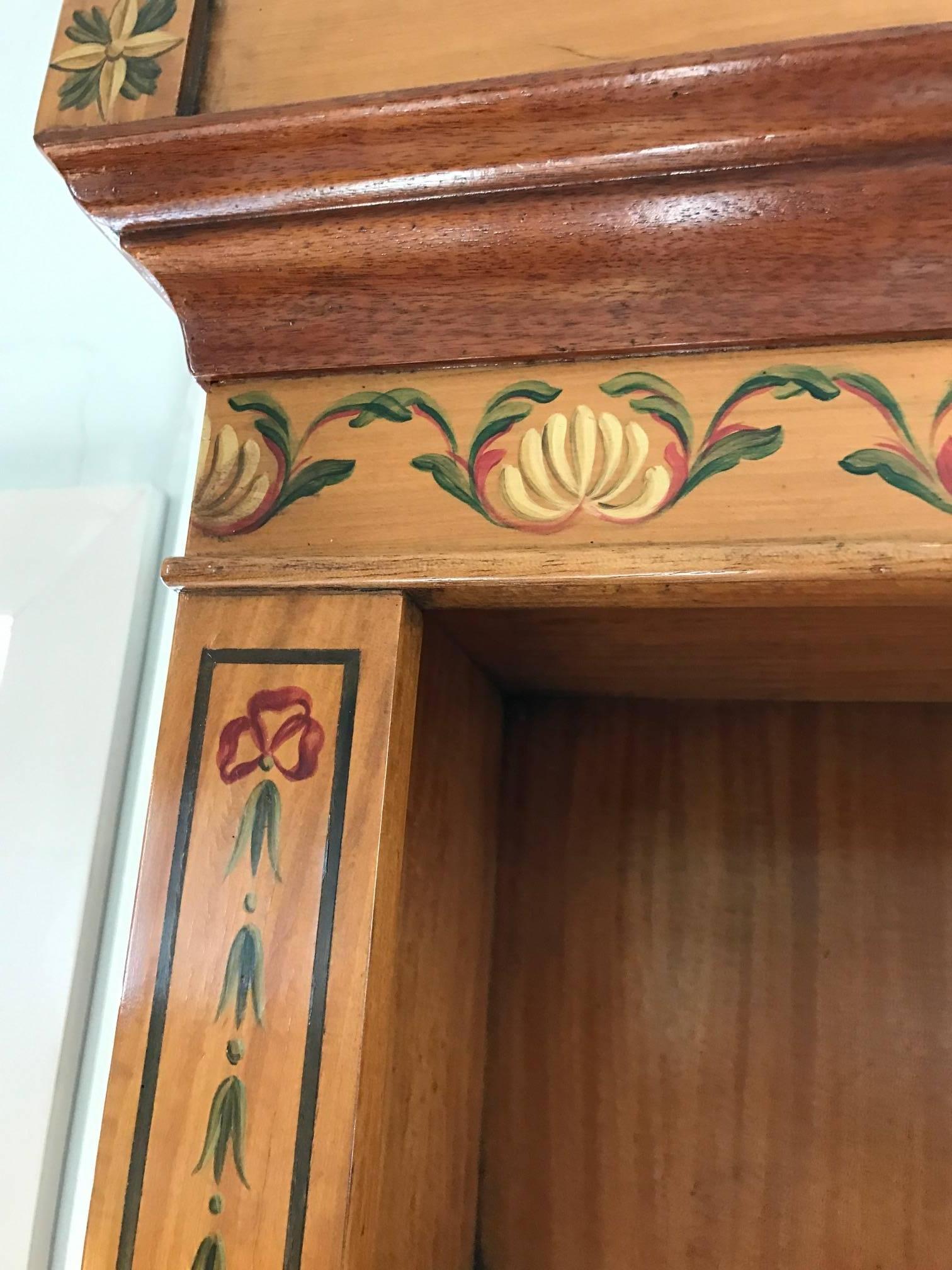 Lovely hand-painted satinwood two-piece cabinet having adjustable shelves on top for books or display, and two doors below with oval floral paintings. Missing one shelf.